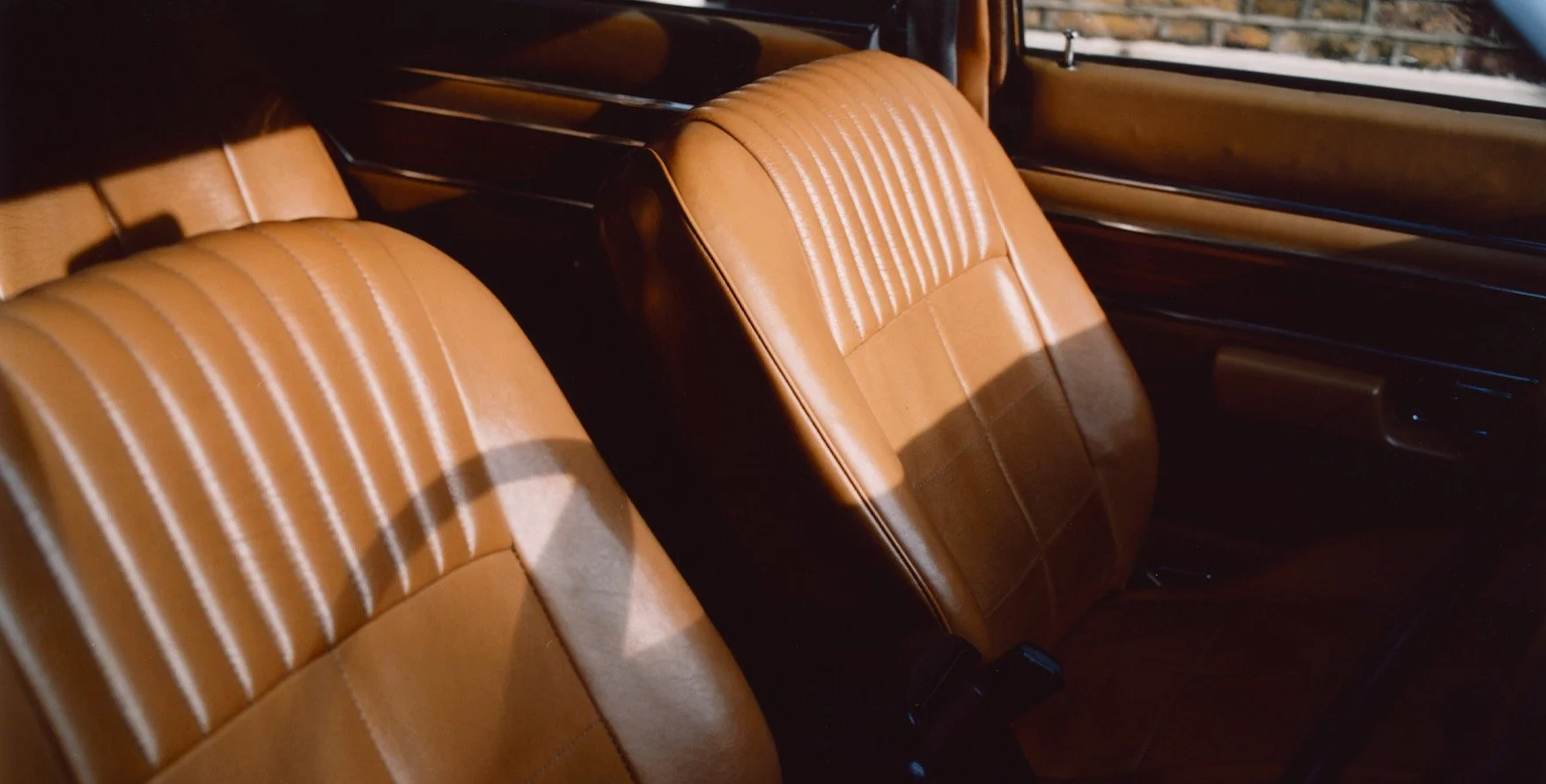 Sunlight shining on tan leather car seats in the interior of a vehicle.