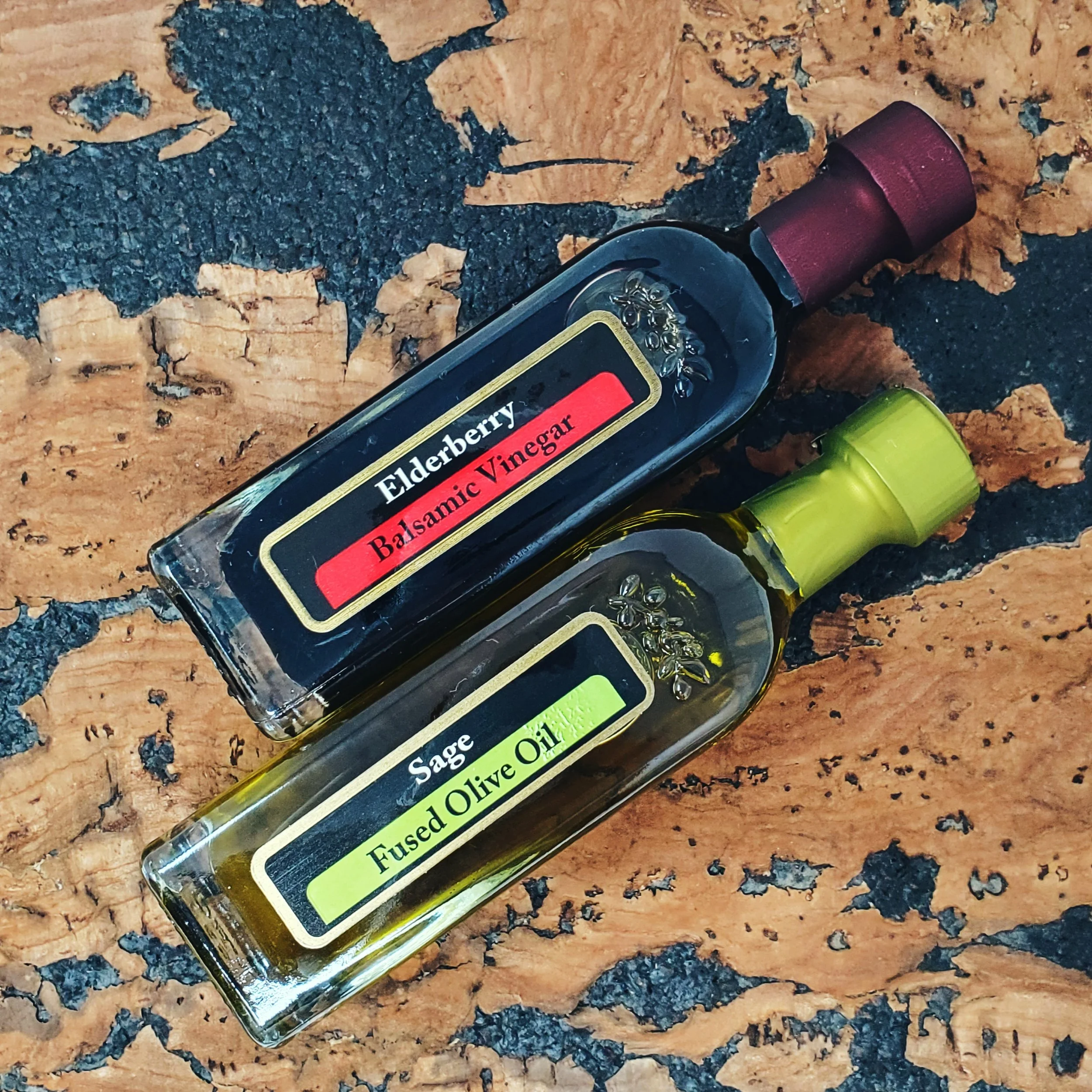 A close-up image of a bottle of flavored vinegar with a label reading 'Elderberry', 'Probiotic Vinegar', and 'Fused' on a wooden surface with black and brown textures.