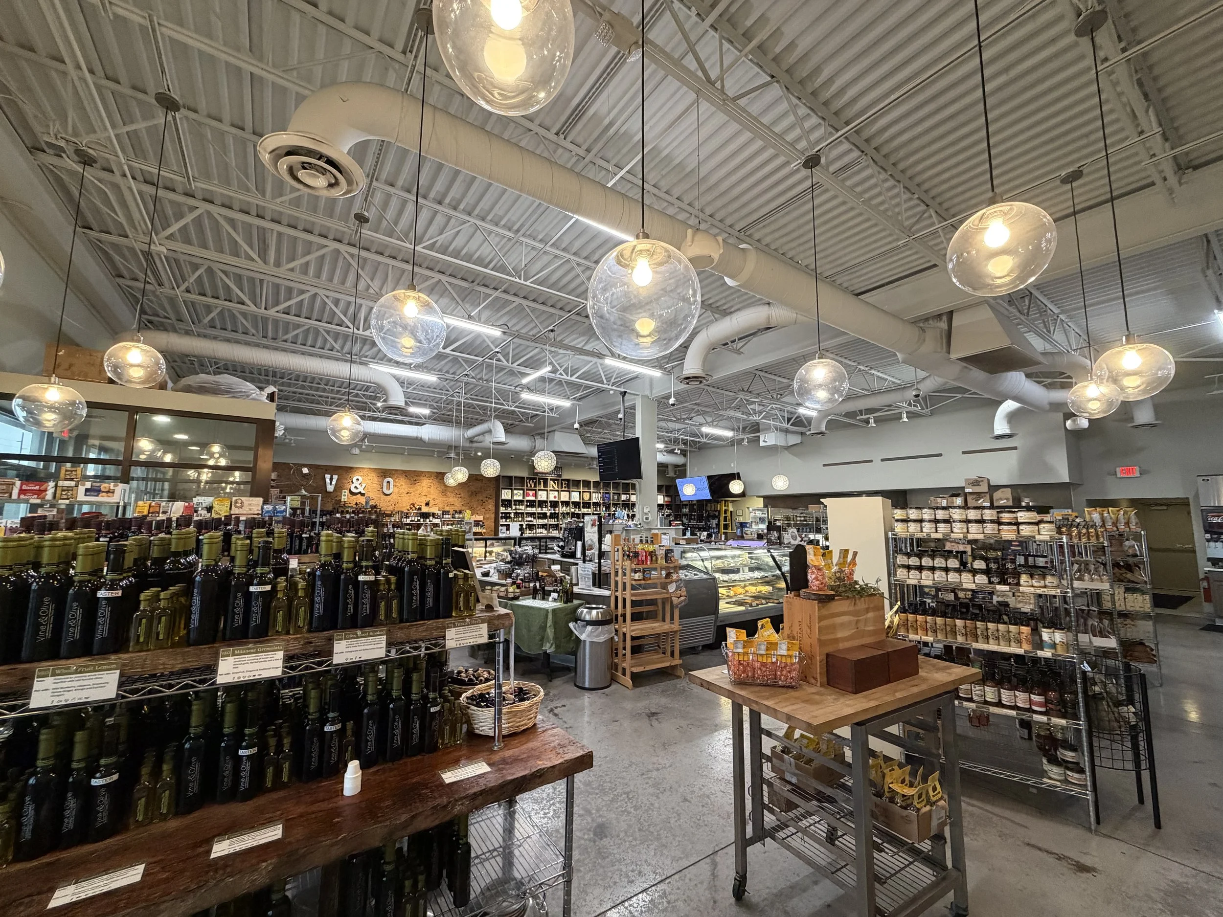 Interior of a grocery store with shelves of wine bottles, oil and vinegar, pasta, and other food items.