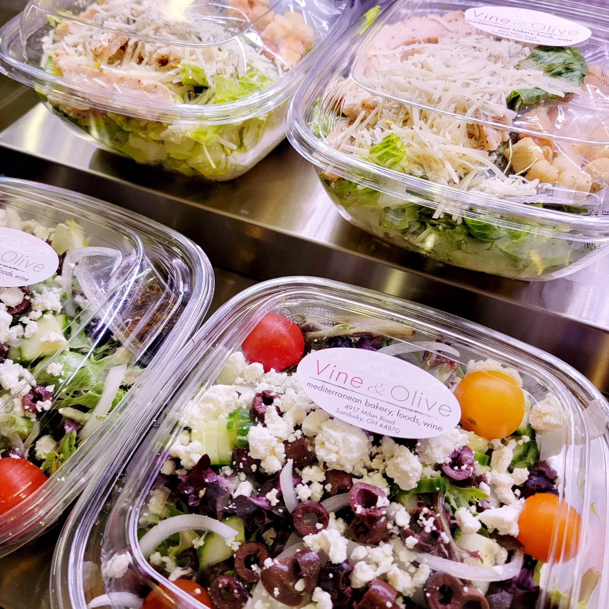 Assorted pre-packaged salads with grilled chicken, cheese, and vegetables in clear plastic containers.