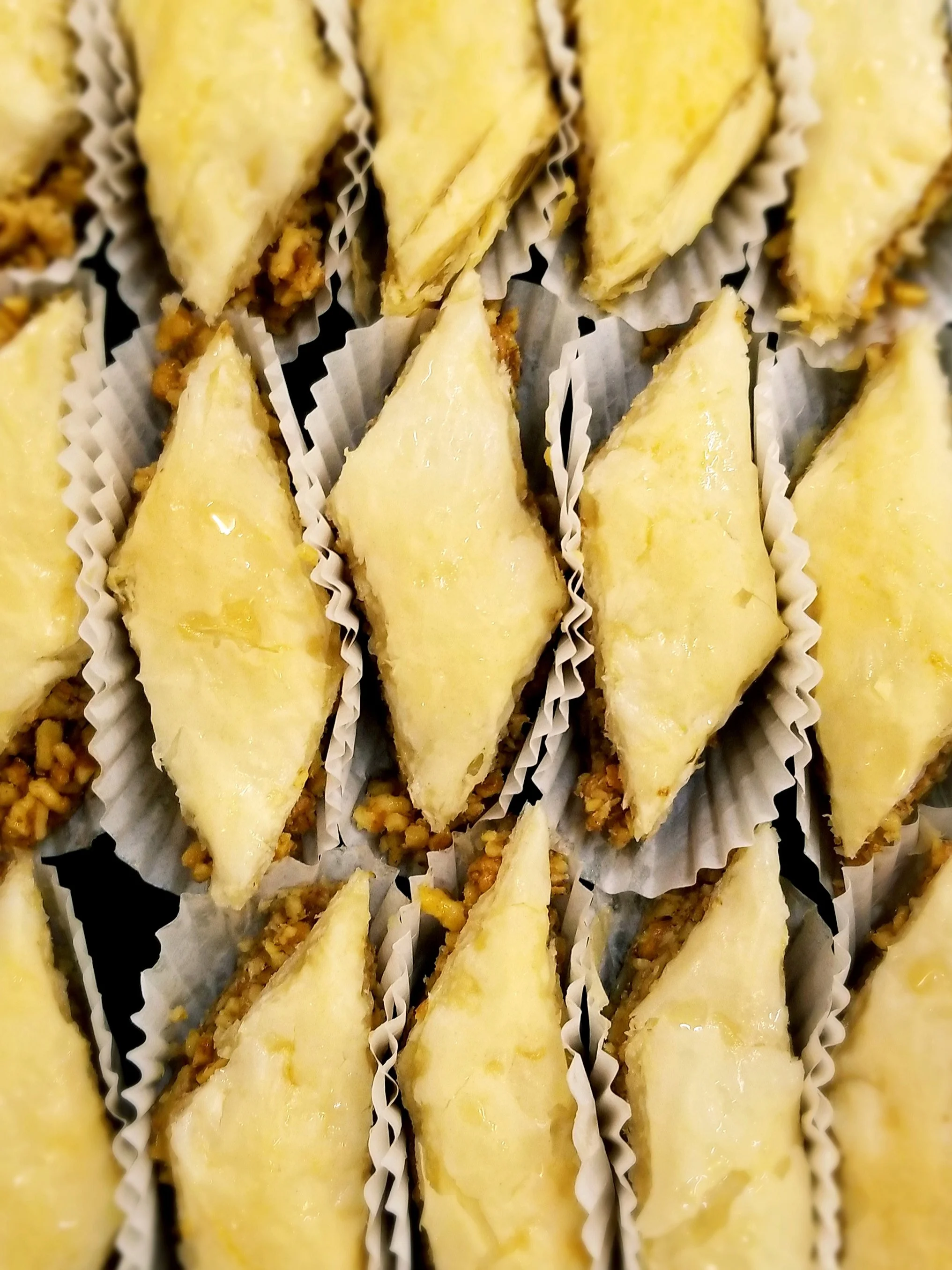 Close-up of several slices of lemon meringue pie with crust, lemon filling, and meringue topping on individual paper liners.