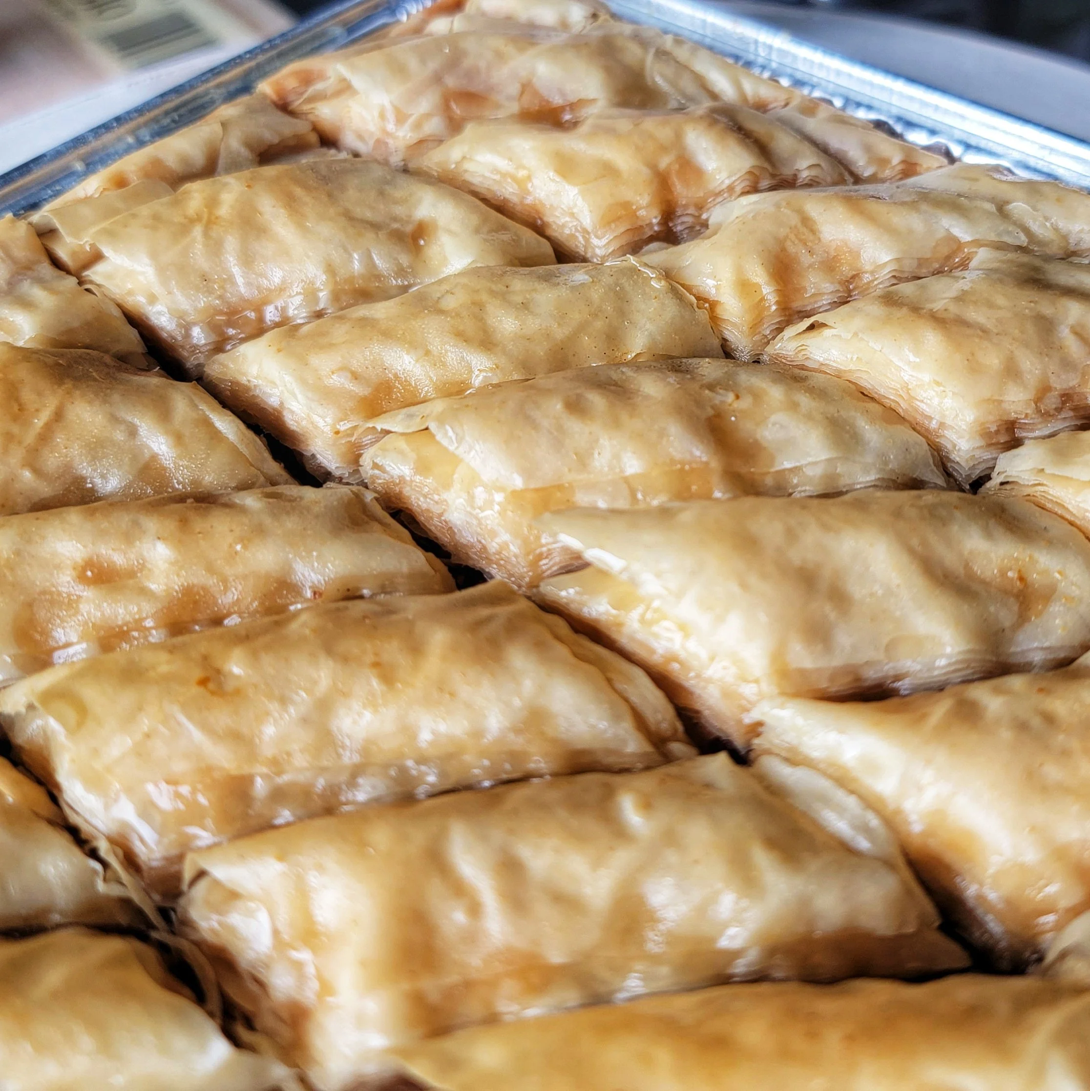 Close-up of baked baklava with golden, flaky phyllo dough layered with chopped nuts and drizzled with honey.