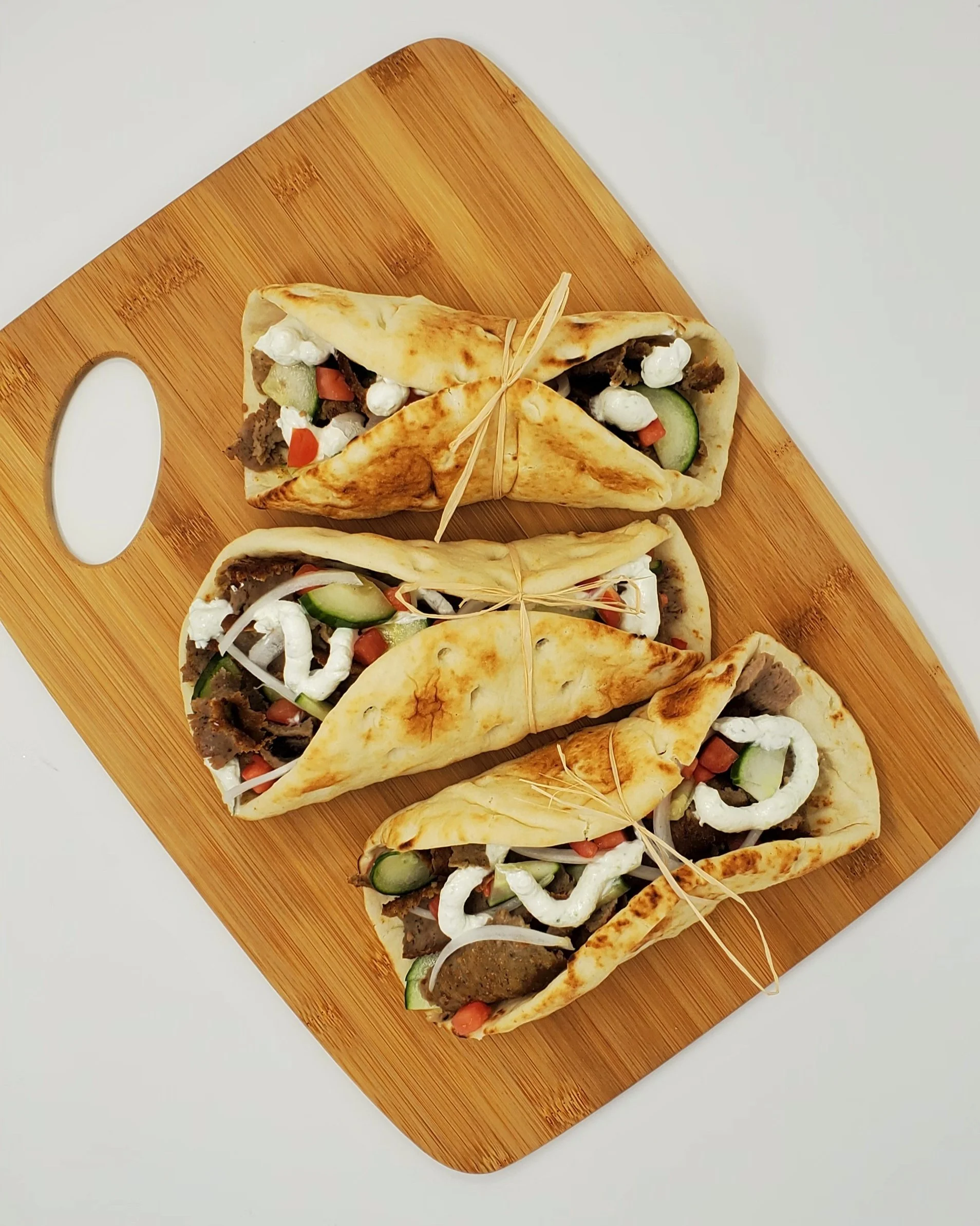 Fresh lamb or chicken gyros on a wooden serving board, accompanied by a Mediterranean side dish.