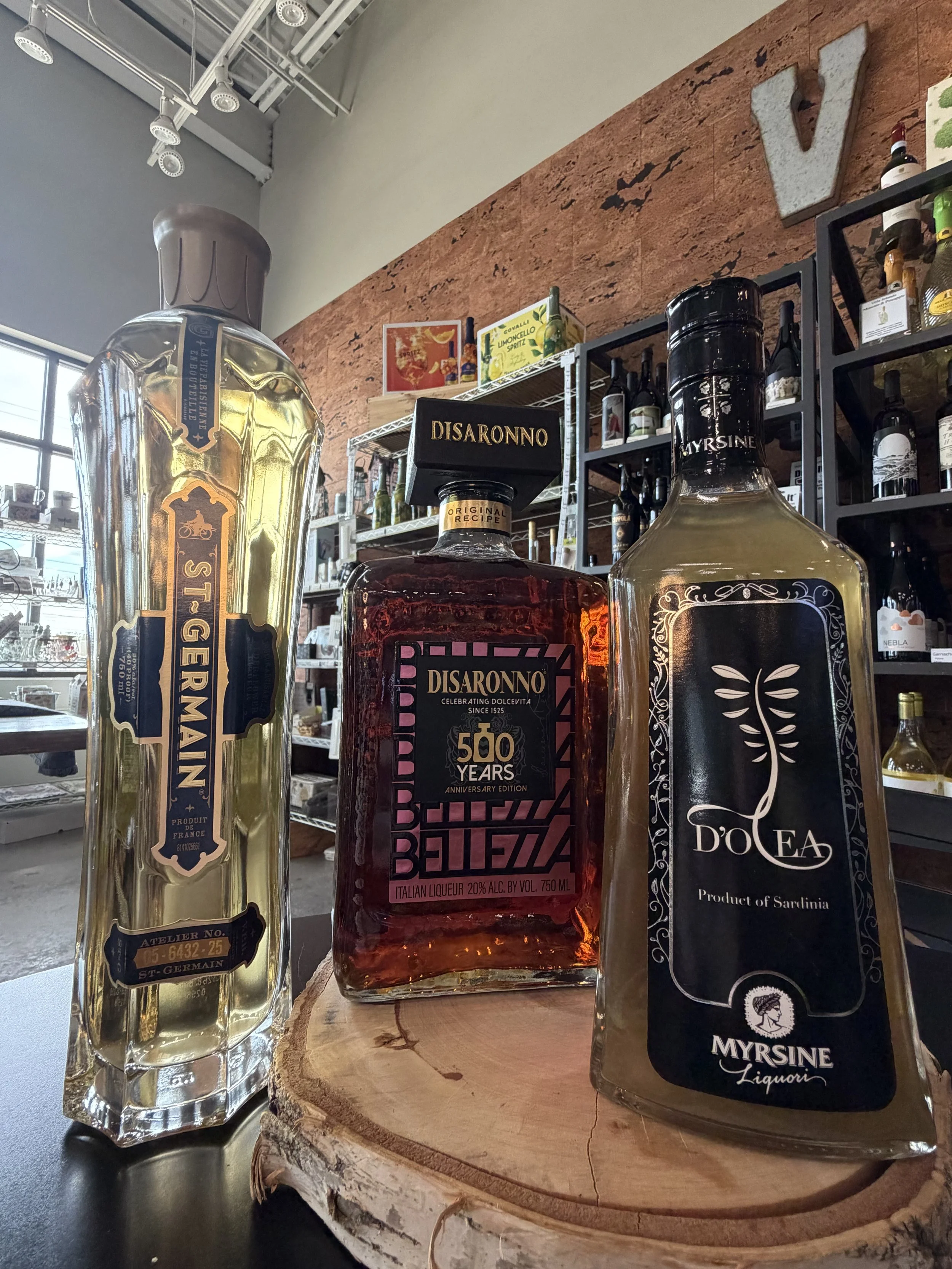 Assorted liquor bottles, including gin and liqueur, displayed on a wooden surface in a store setting.