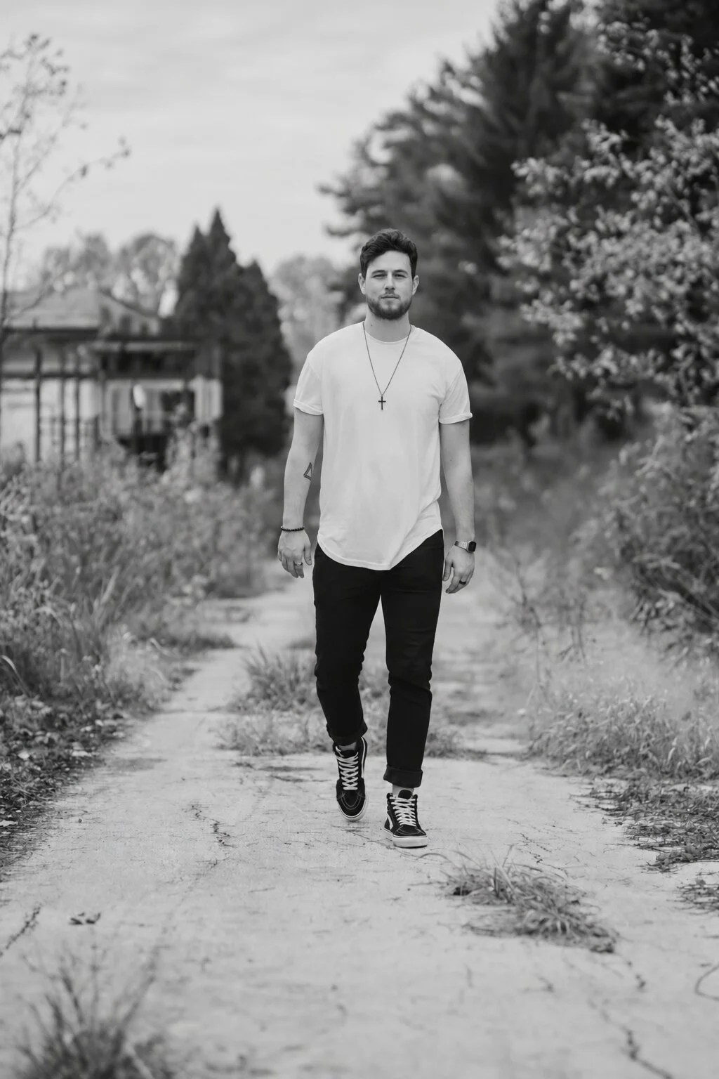 Image of a person waling on a path looking ahead with a small cross necklace.