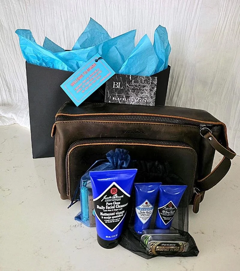 A gift bag with blue tissue paper, a brown toiletry bag, and personal care products including facial cleansers, shave gel, and moisturizer.