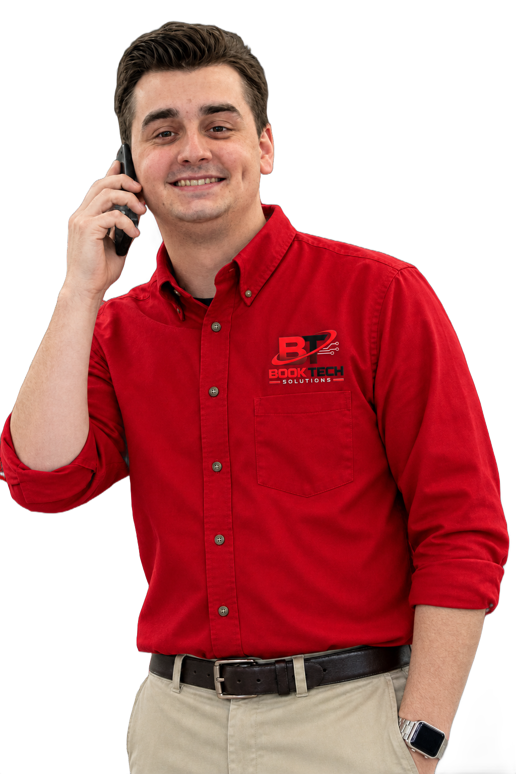 A smiling man with brown hair wearing a red company shirt talking on a cell phone against a black background.