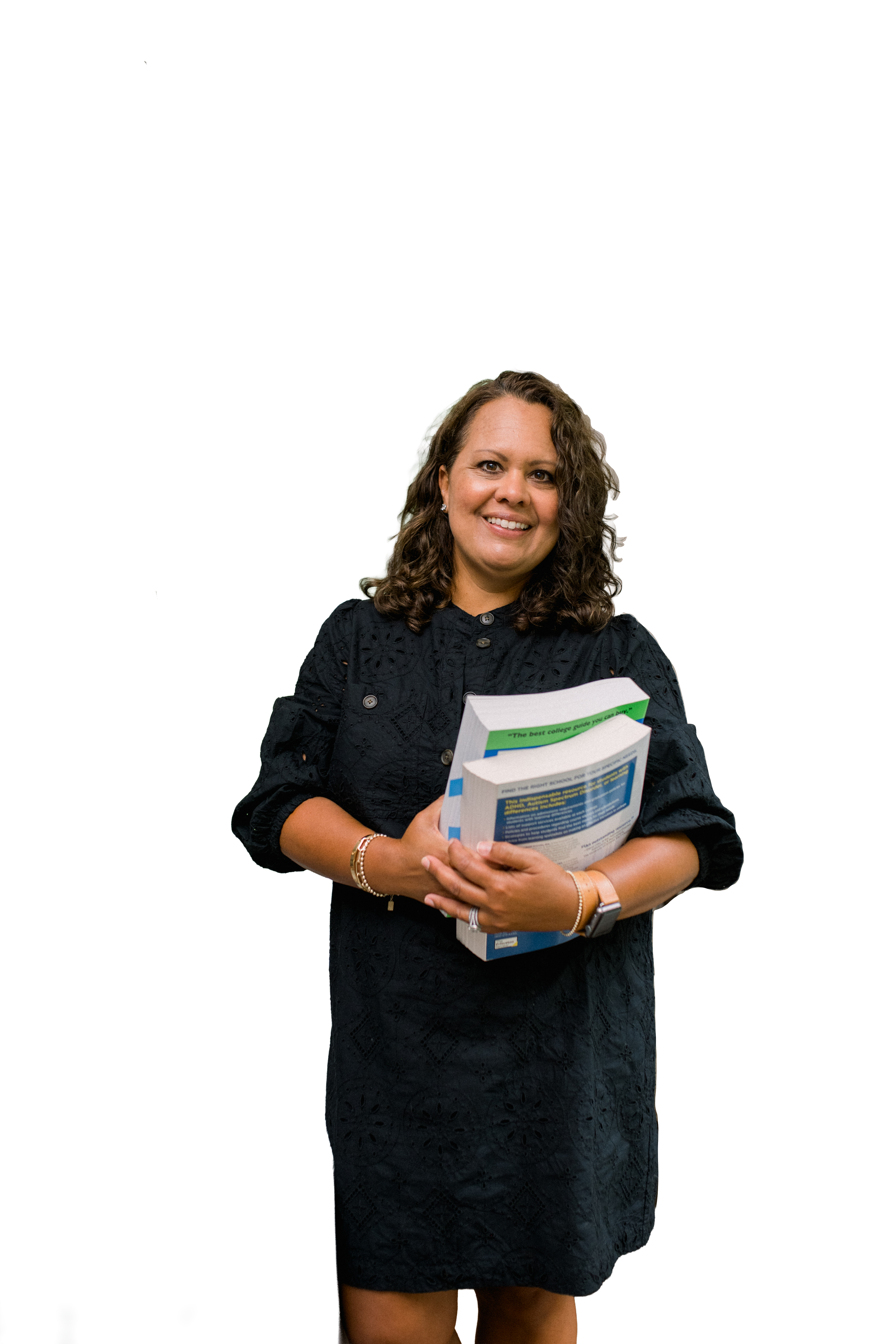 An educational consultant, Stephanie Turnier Mitchell, with curly brown hair wearing a black dress holds a stack of books and smiles at the camera.