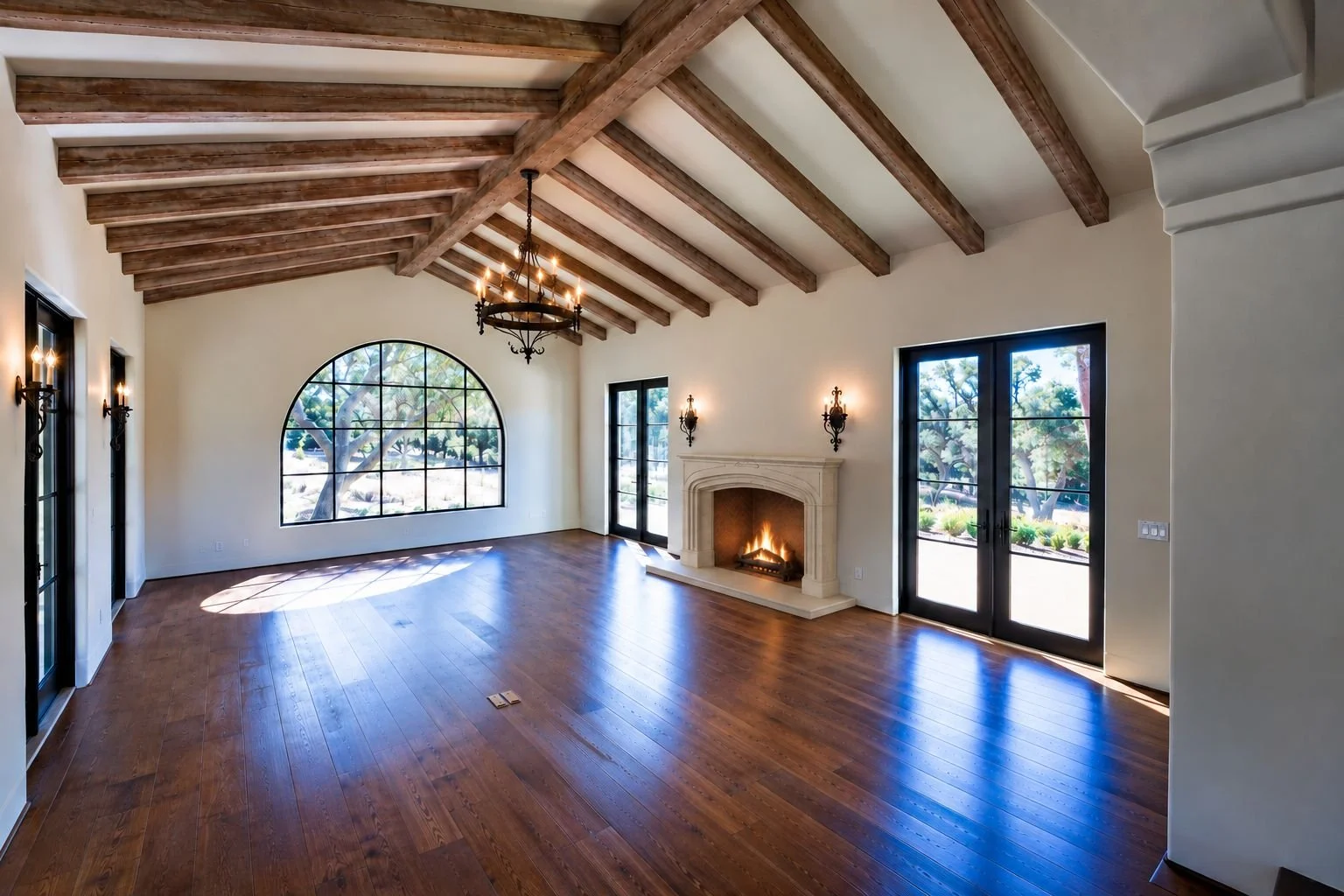 Spacious living room with high wooden ceiling beams, a fireplace, large window and glass doors, hardwood flooring, and elegant light fixtures.
