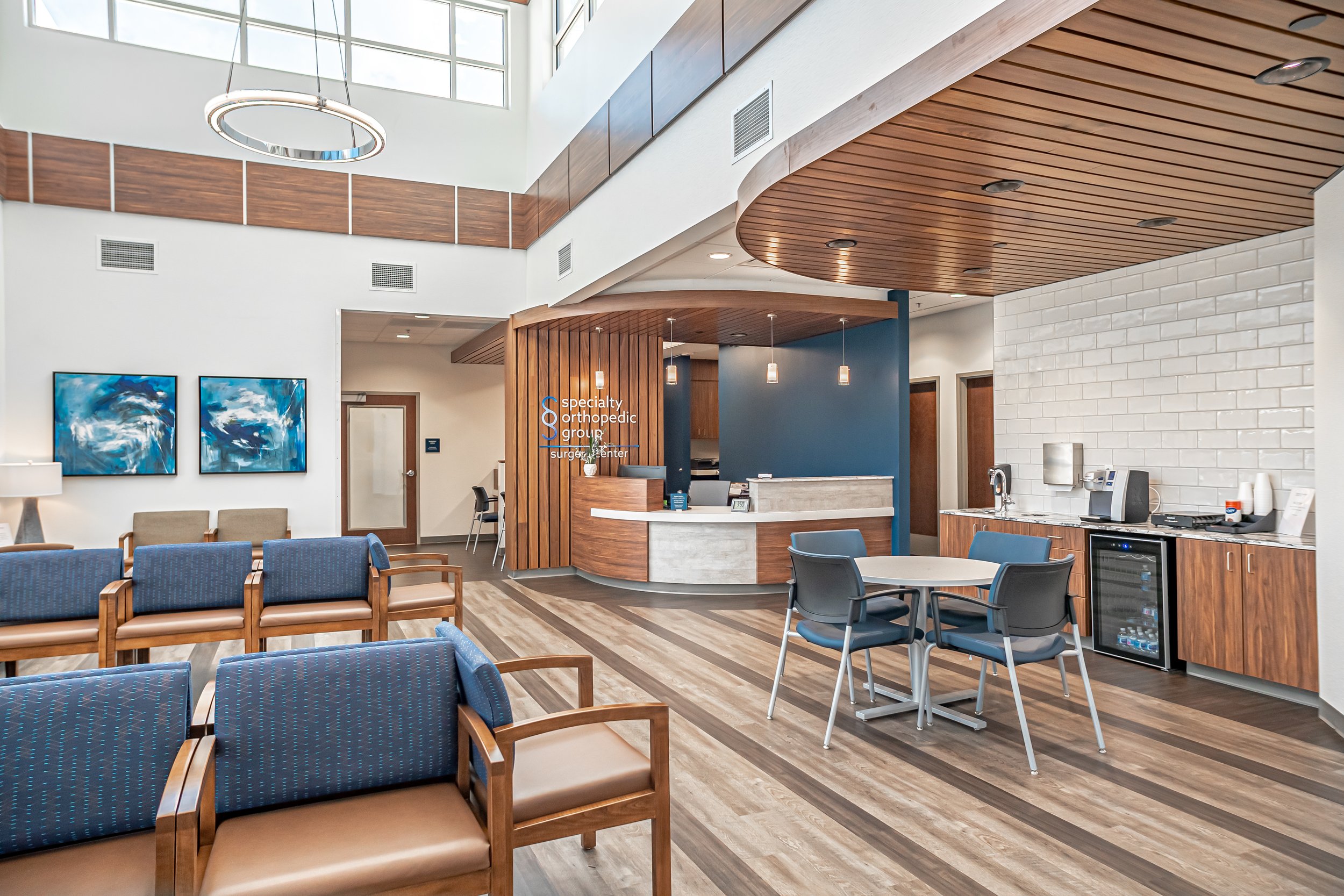 Interior of a modern medical waiting room with chairs, a reception desk, and medical equipment.