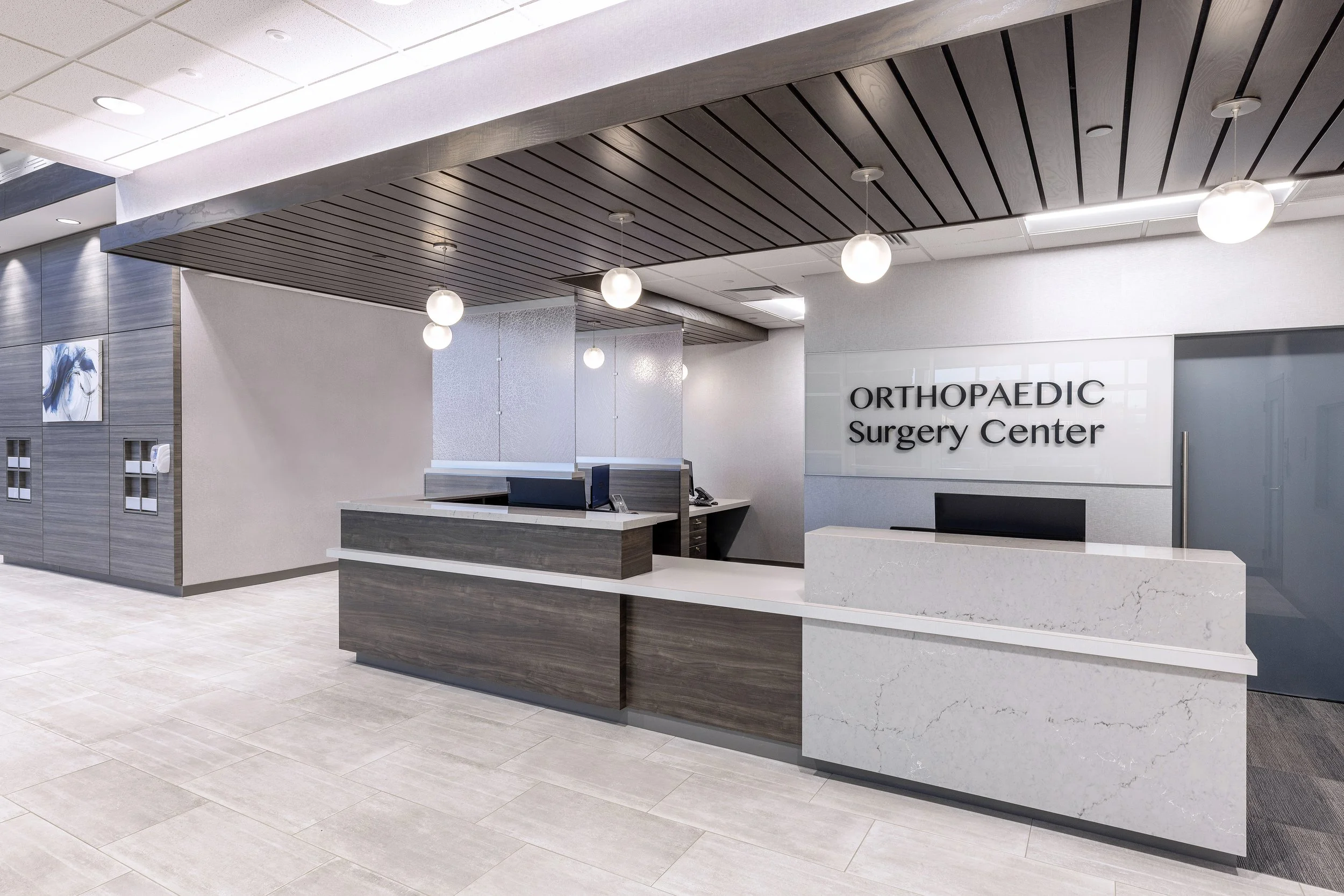 Reception area of an orthopedic surgery center with a modern design, a desk, and signage.