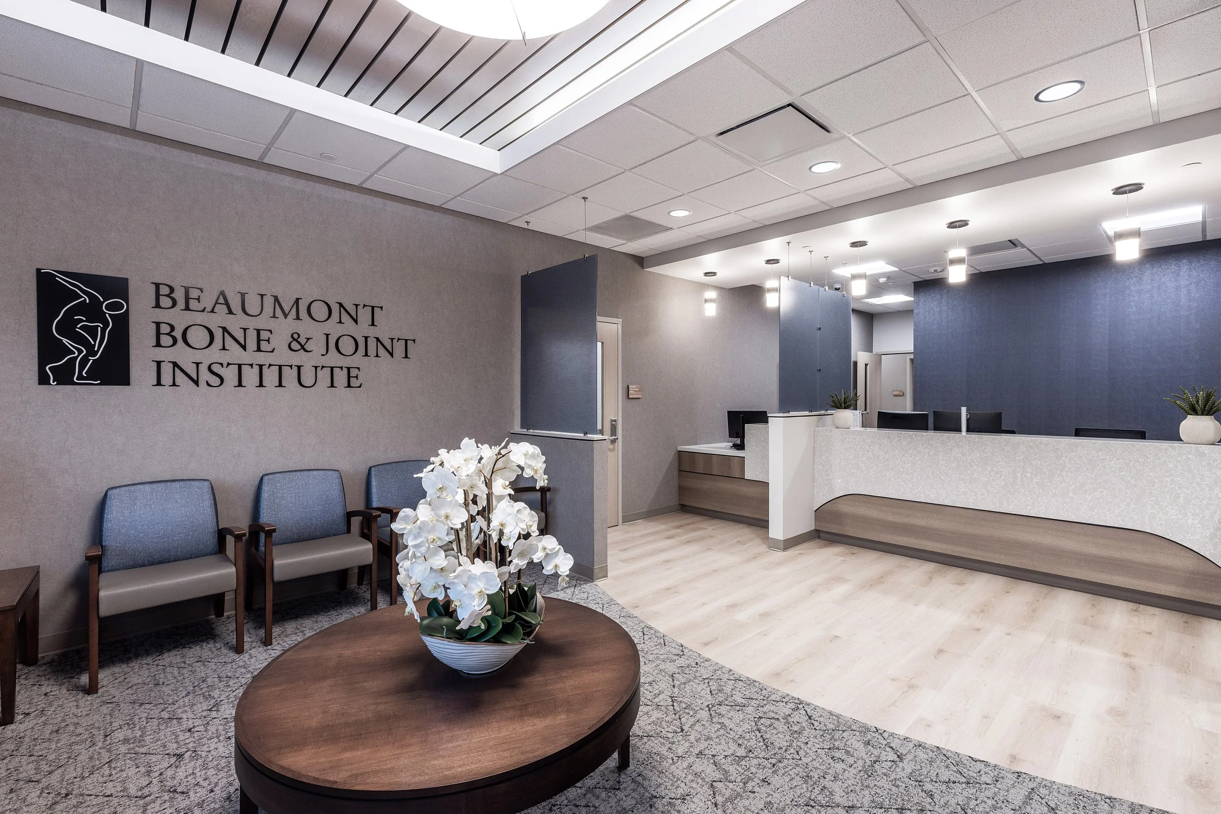 Interior of Beaumont Bone & Joint Institute, showing a waiting area with chairs, a table with white orchids, and a reception desk.