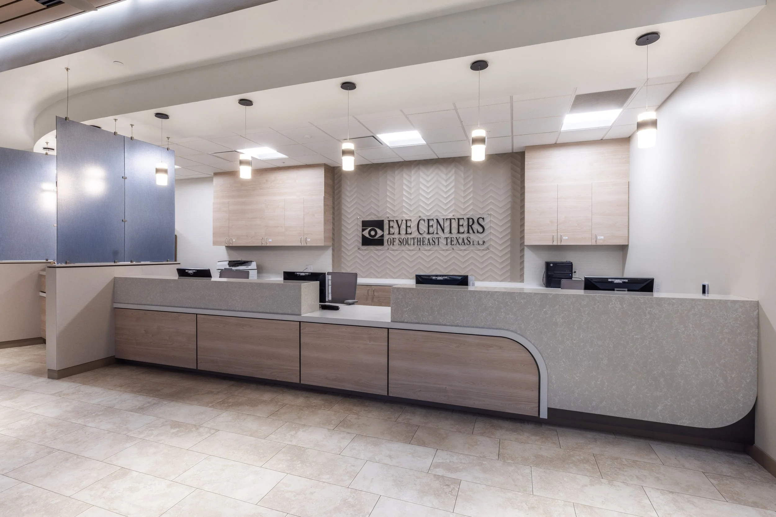 Reception area of Eye Centers of Southeast Texas with a curved counter, monitors, and a sign on the wall.