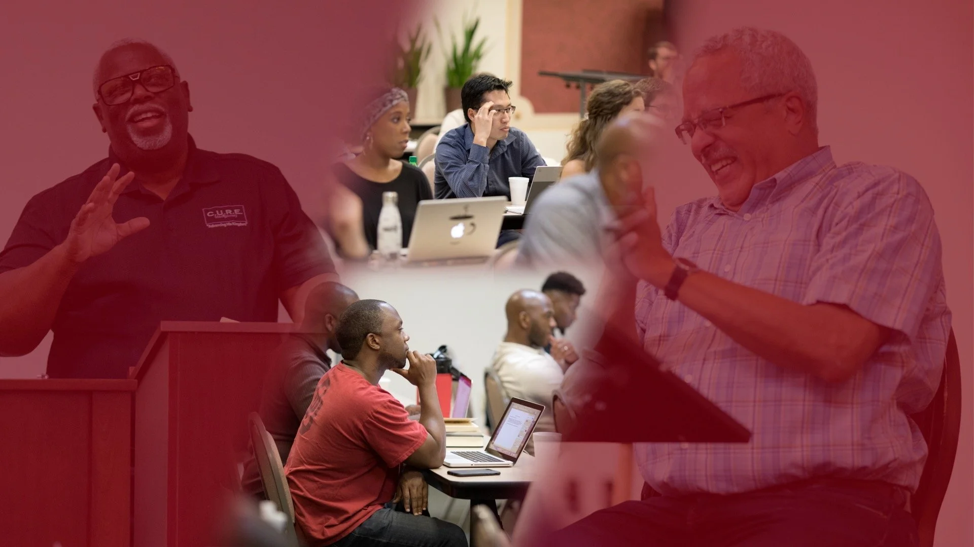 A diverse group of people attending a conference or seminar, some taking notes on laptops and others listening, with a woman and a man engaged in conversation and smiling.