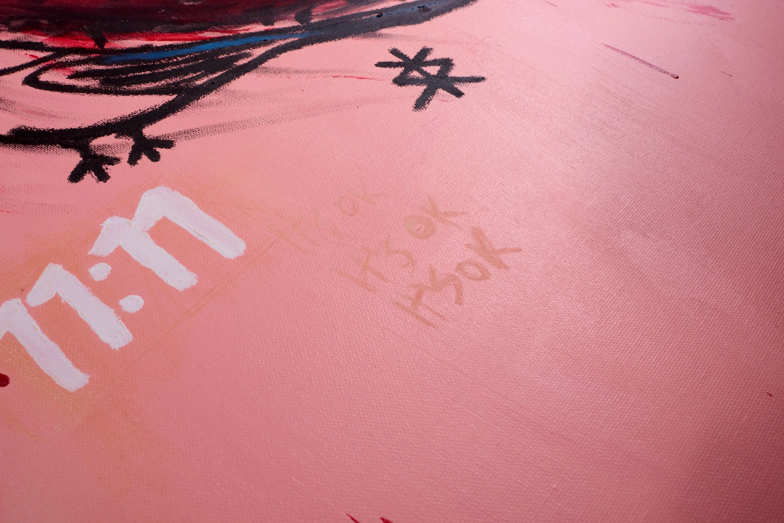 Close-up of pink painting with black and white painted text and symbols