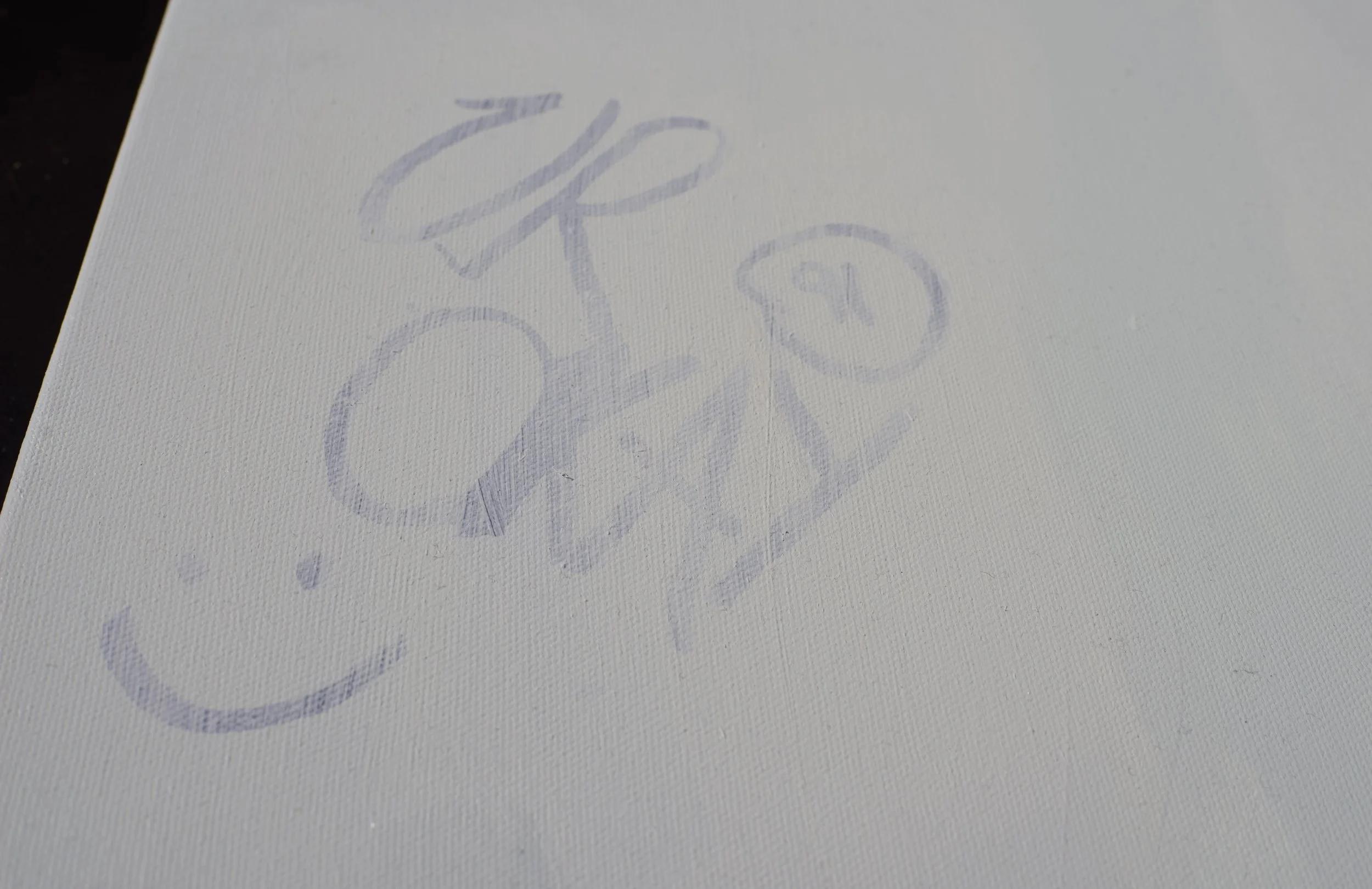 Close-up of a piece of white paper with a faint, light purple, hand-drawn sketch of a bicycle and flowers.