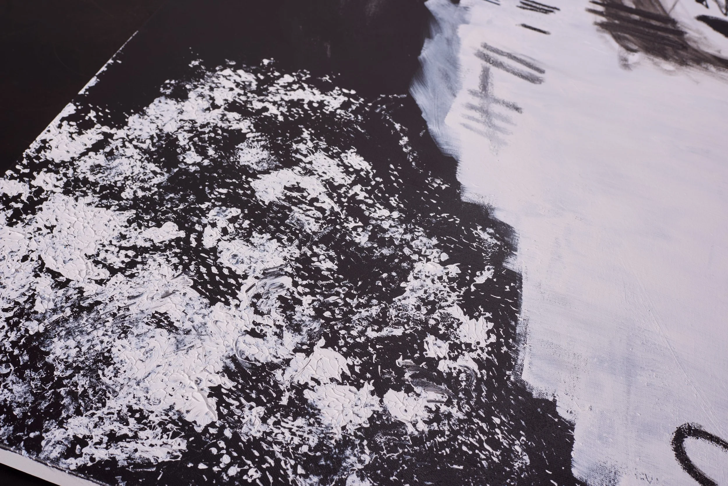 Close-up of an abstract black-and-white painting with textured white patches on a black background and white brushstrokes on the right side.