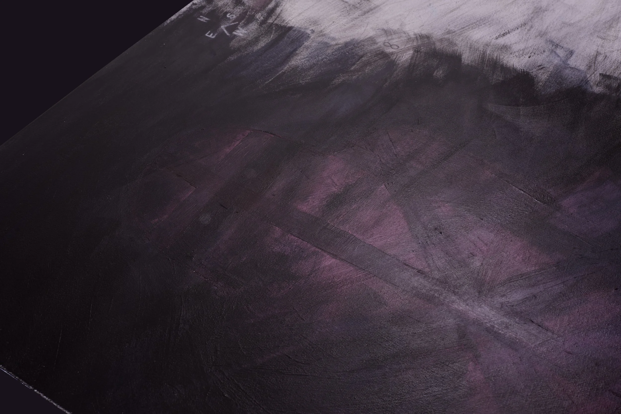 Close-up of a dark, textured surface with faint purple and pink hues and some chalk markings.