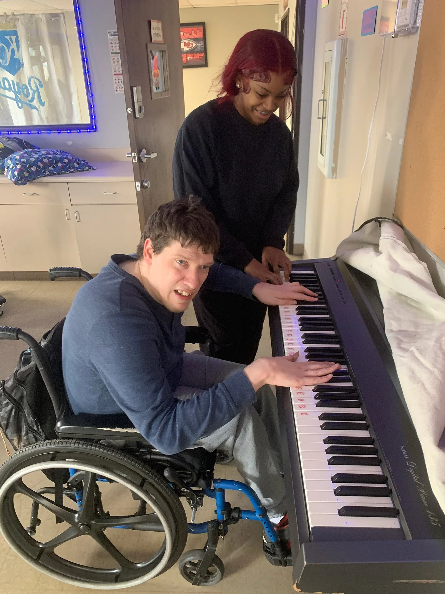 Client playing the keyboard while sitting in his wheelchair