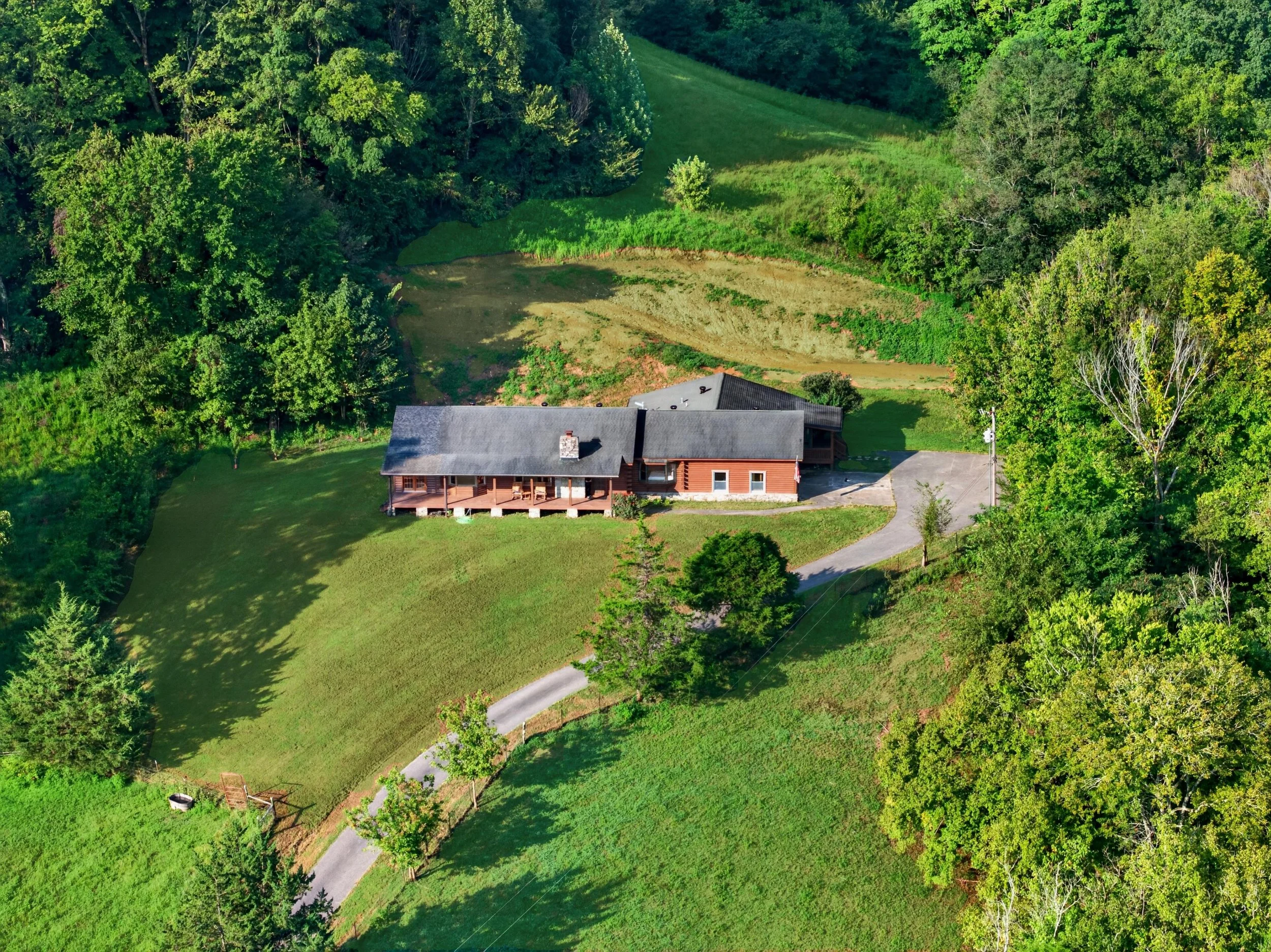 Aerial view of Refuge Ranch, a 30-acre country retreat in Lynnvillle, Tennessee, surrounded by lush green trees and rolling countryside.