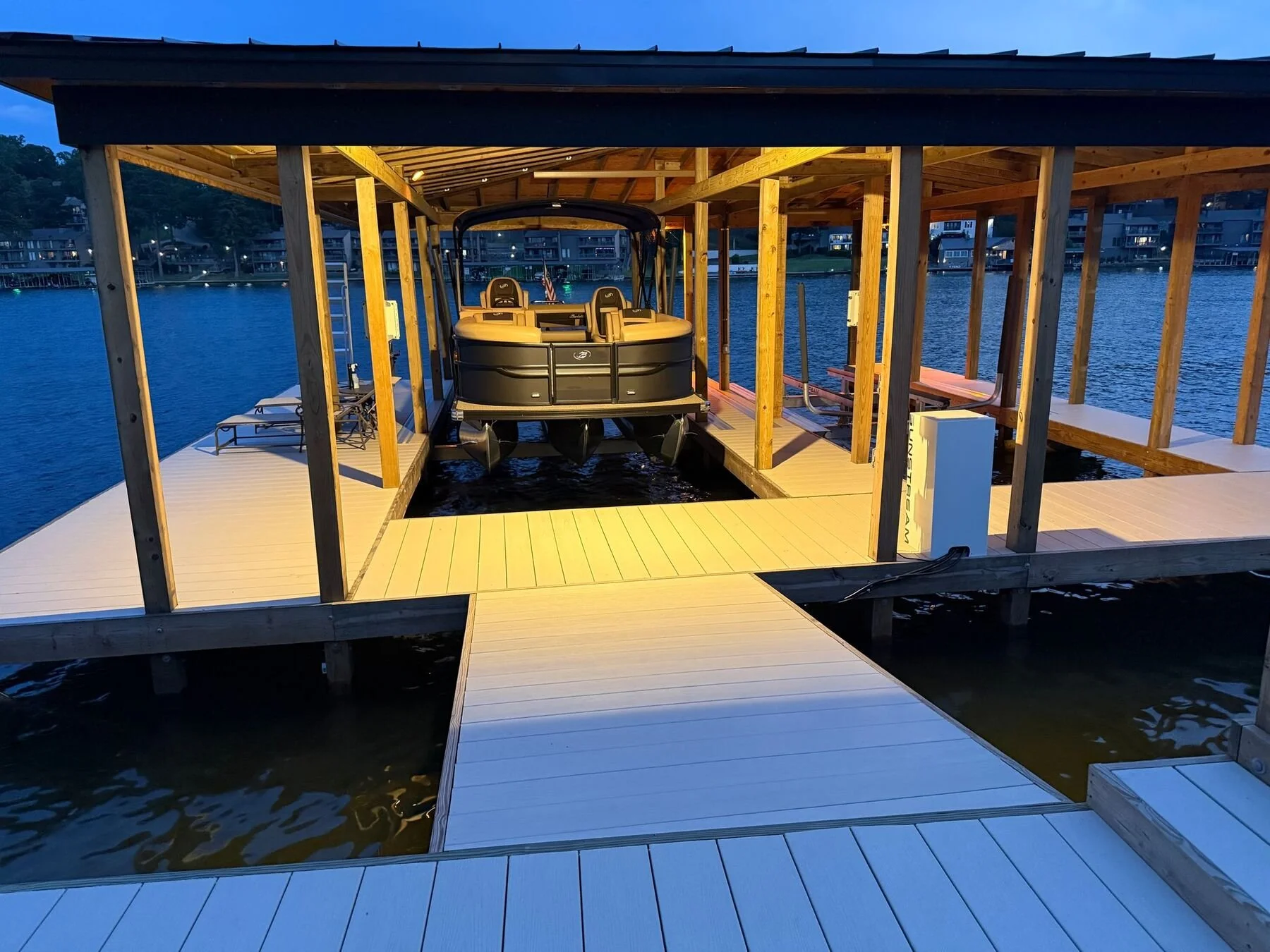 Boat dock lit at dusk with a pontoon in the slip, Lake Hamilton