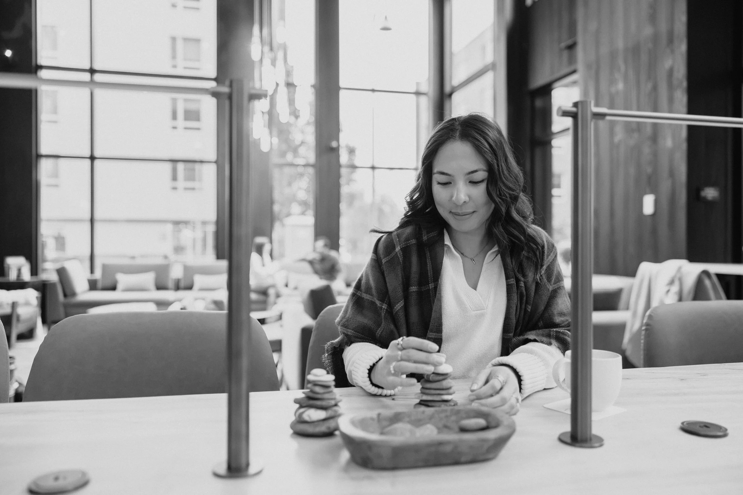 A woman in a cafe playing Jenga while looking at her phone.