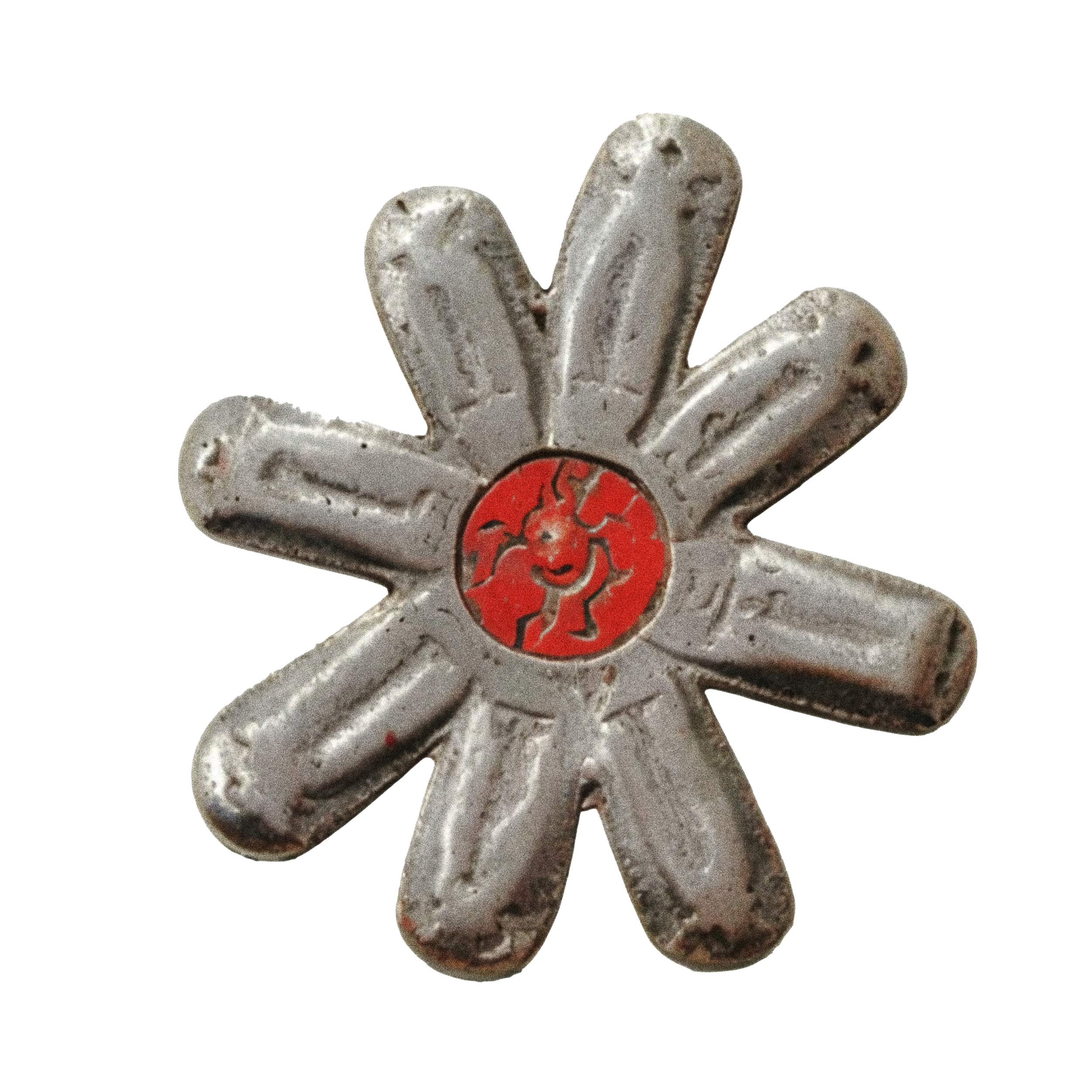 Close-up of a vintage metallic flower-shaped object with a red center, aged and weathered.