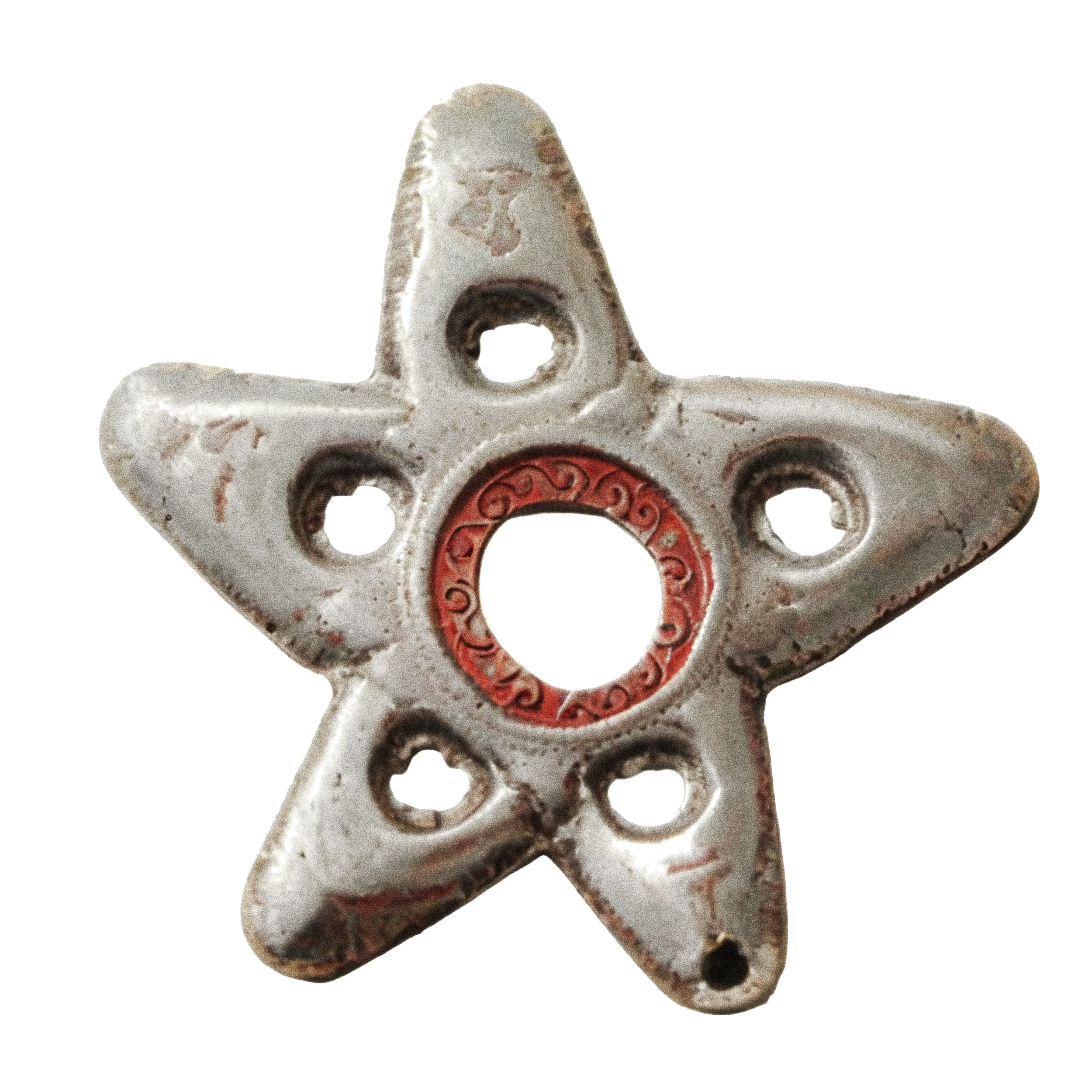 Close-up of a decorative ceramic object with holes, red intricate patterns, and an weathered, sandy surface.