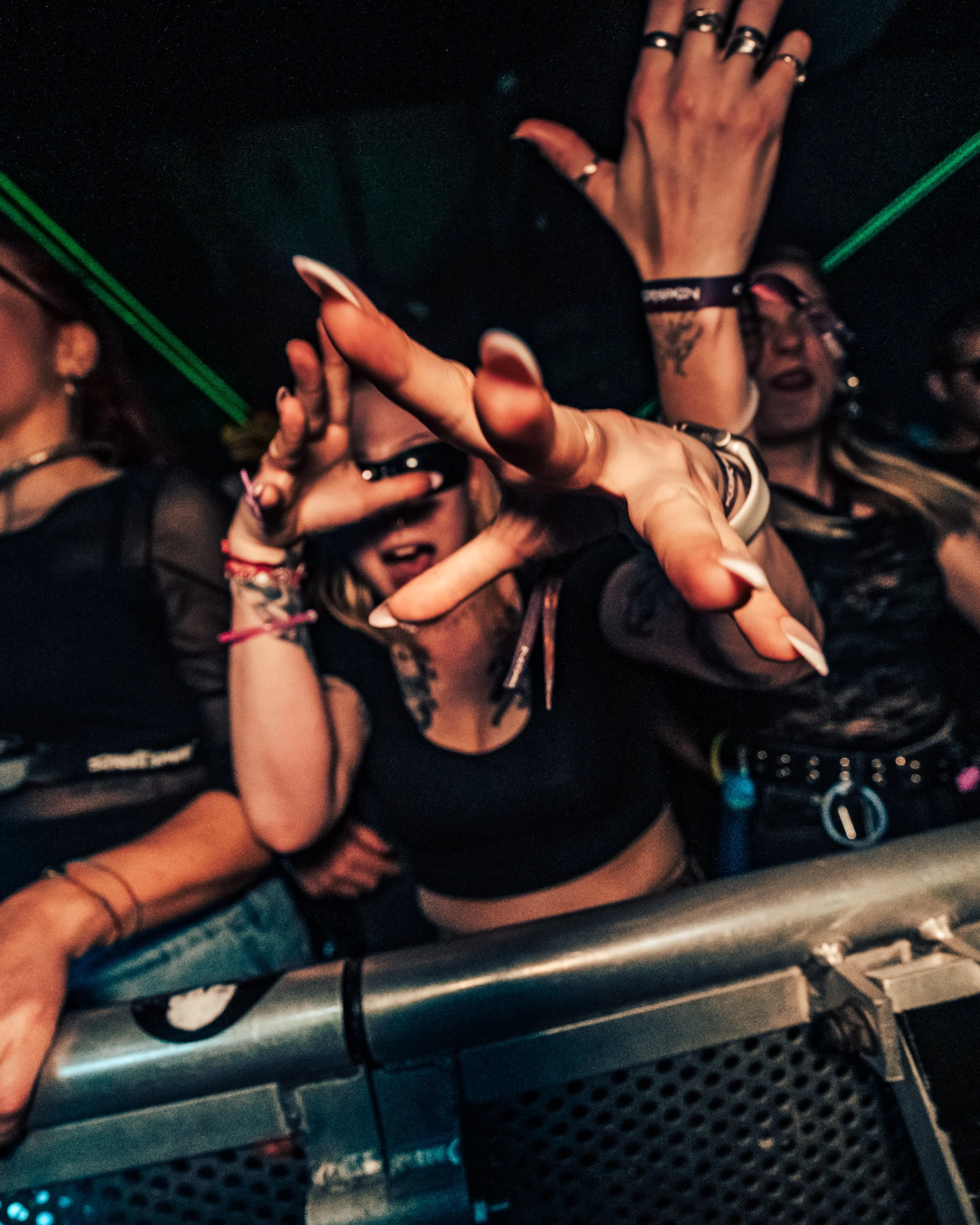 A group of people at a lively party or club, dancing and enjoying music, with one person in focus reaching out with their hand.