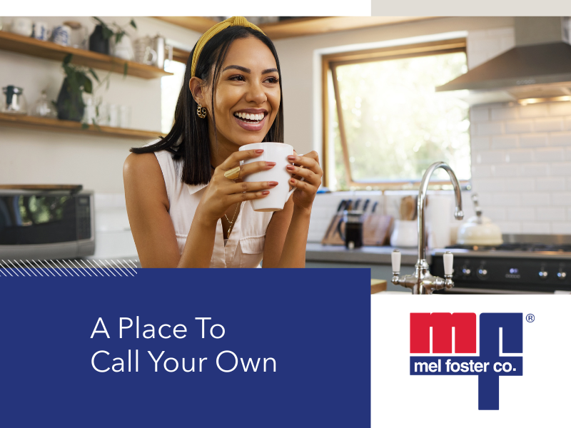 A woman in a kitchen smiling and holding a white mug.