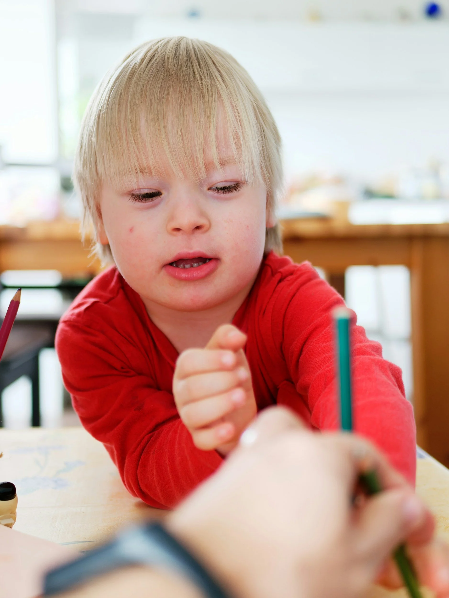 Young child concentrating on a creative activity at a table.