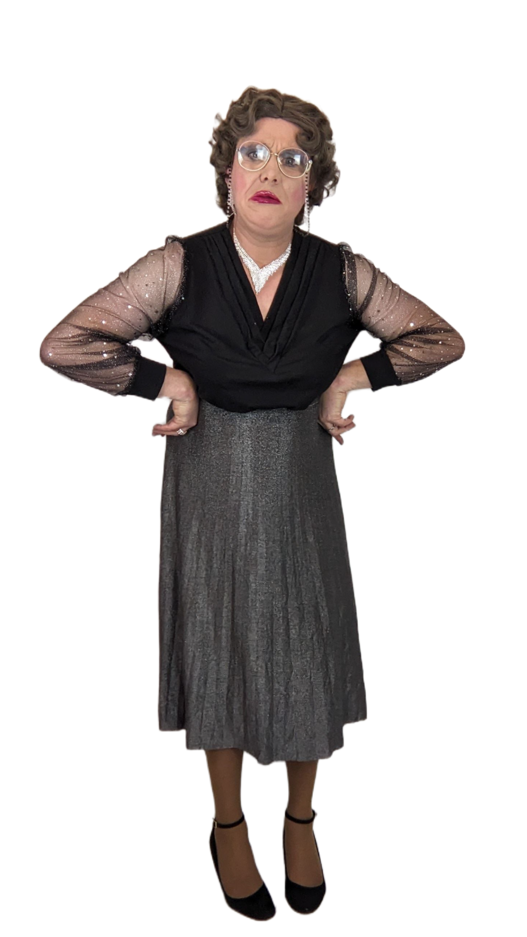 Granny Muffin trägt ein elegantes, glitzerndes Kleid mit schwarzen, durchsichtigen Ärmel. Sie trägt eine Perlenkette und eine Brille, wirkt überrascht oder verwirrt, hat kurze, lockige Haare und steht mit den Händen an den Hüften.