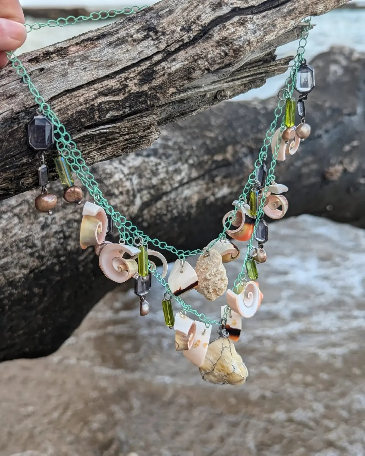 Double layered necklace featuring shells, black pearls, and a fossilized coral in the center