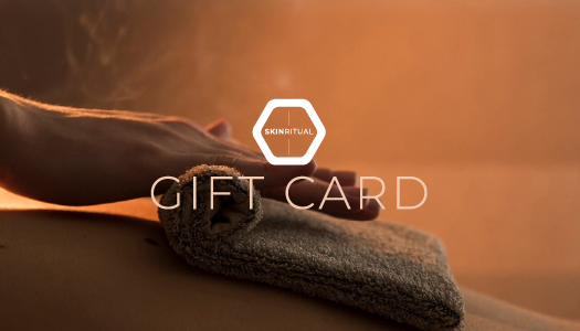 Close-up of a gift card and a rolled towel on a wooden surface with a warm background at Rejuvenate Wellness in Florence Kentucky