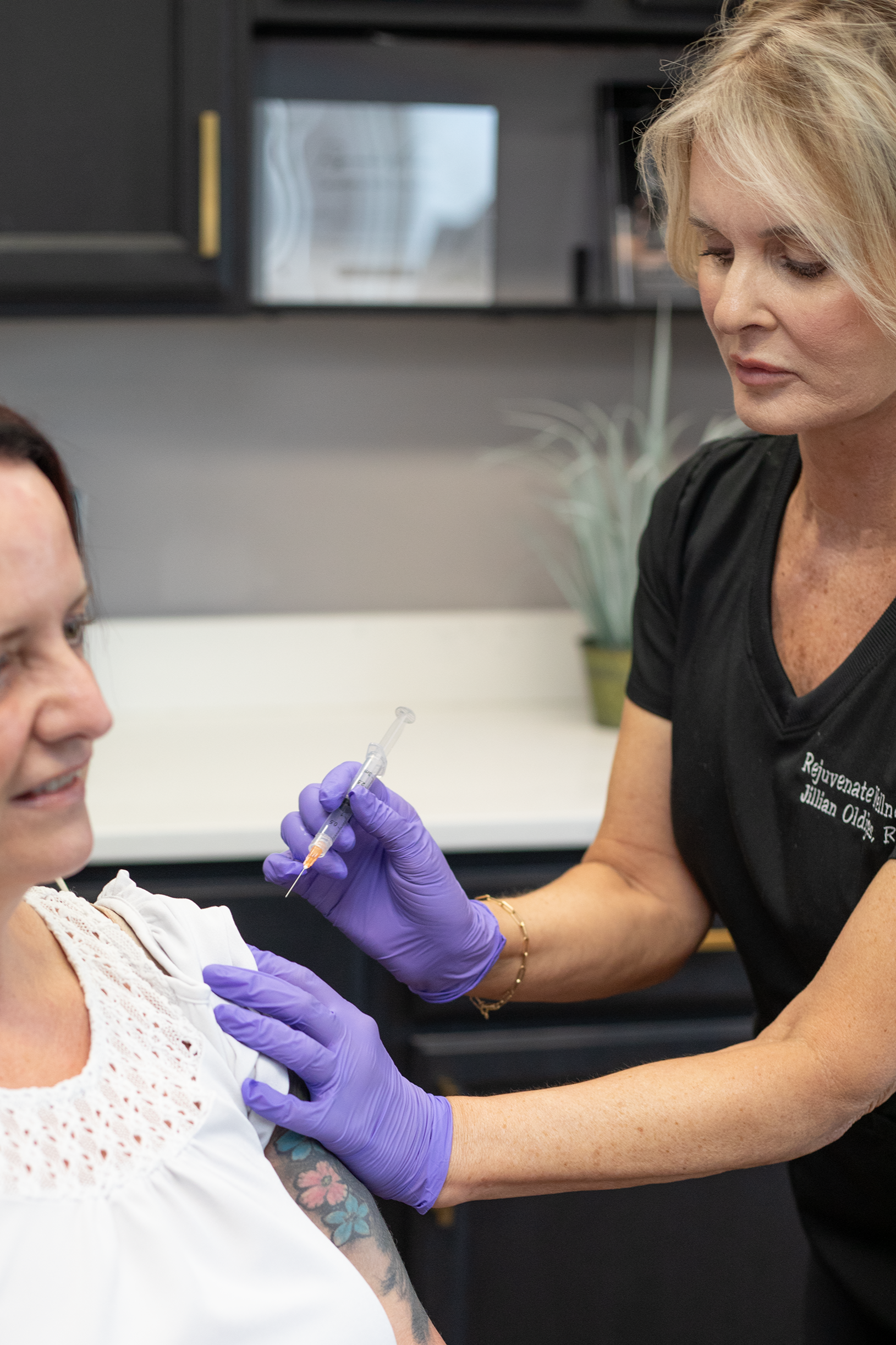 A healthcare worker administering a vaccine shot to a woman in a medical setting at Rejuvenate Wellness in Florence Kentucky