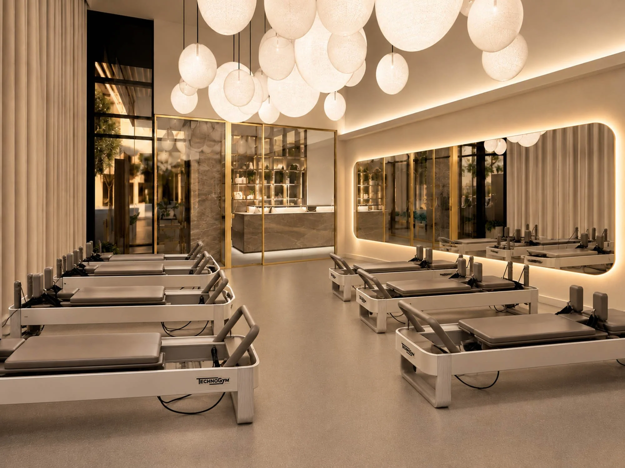 A modern pilates studio, ceiling lights resembling paper lanterns, and a sleek interior with gold accents, mirrors, and decorative shelves.