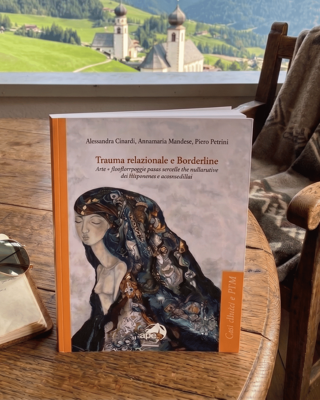 Libro sulla scrivania con paesaggio di montagna e chiese in lontananza.