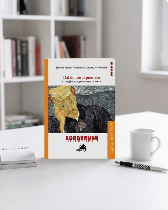 Libro intitolato 'Dal dolore al pensiero' di Jennifer Barone, Annamaria Mandea e Piero Petrini, con copertina di Paul Klee, posato su tavolo vicino a tazza di caffè, penna e quaderno, in uno studio con scaffali pieni di libri.