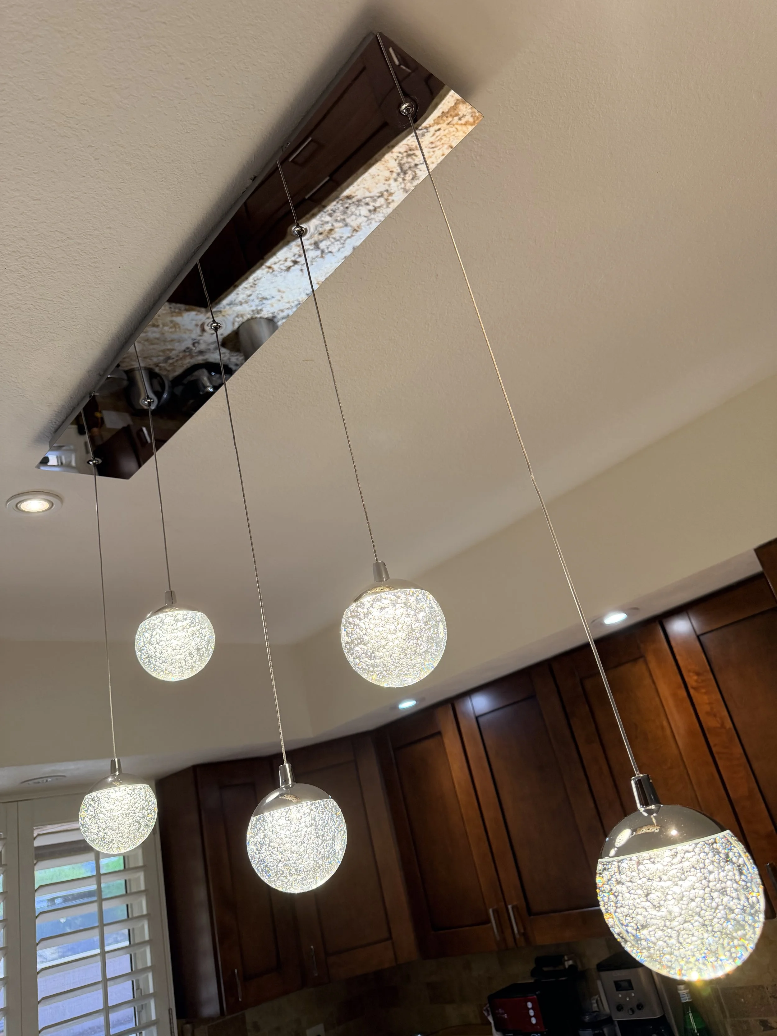 Multiple hanging glass pendant lights with intricate cracked glass design in a kitchen ceiling.