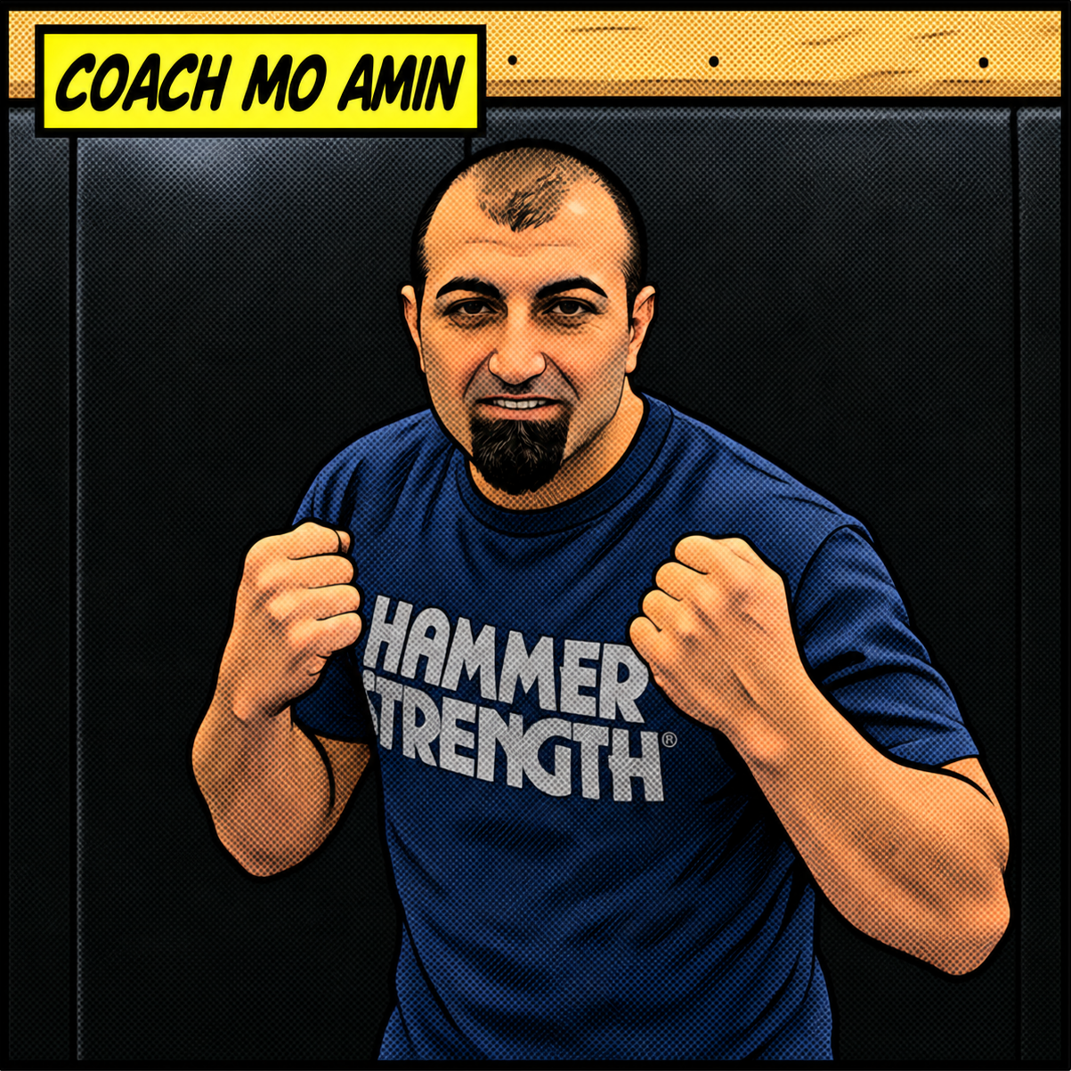 A man in a blue Hammer Strength t-shirt posing with fists raised, standing in front of a black backdrop with a yellow sign that reads 'Coach Mo Amin'.