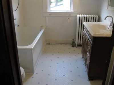 Small bathroom with a bathtub, a sink with a cabinet, a window, and a radiator.