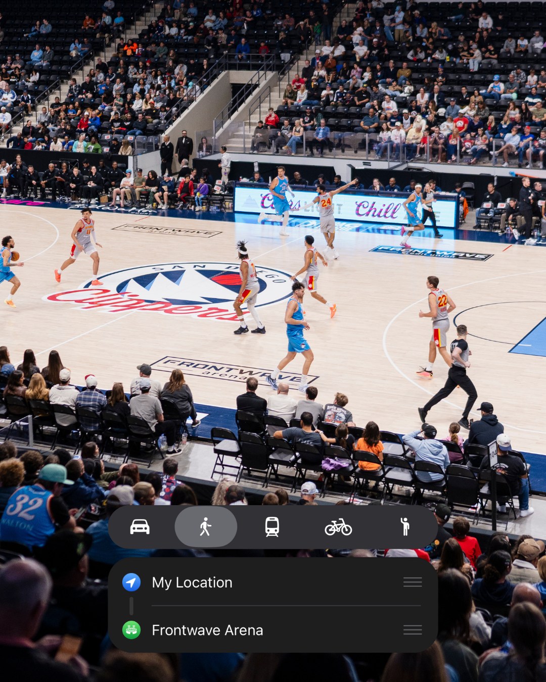 People playing basketball on a court at Frontwave Arena, with spectators watching from the stands.
