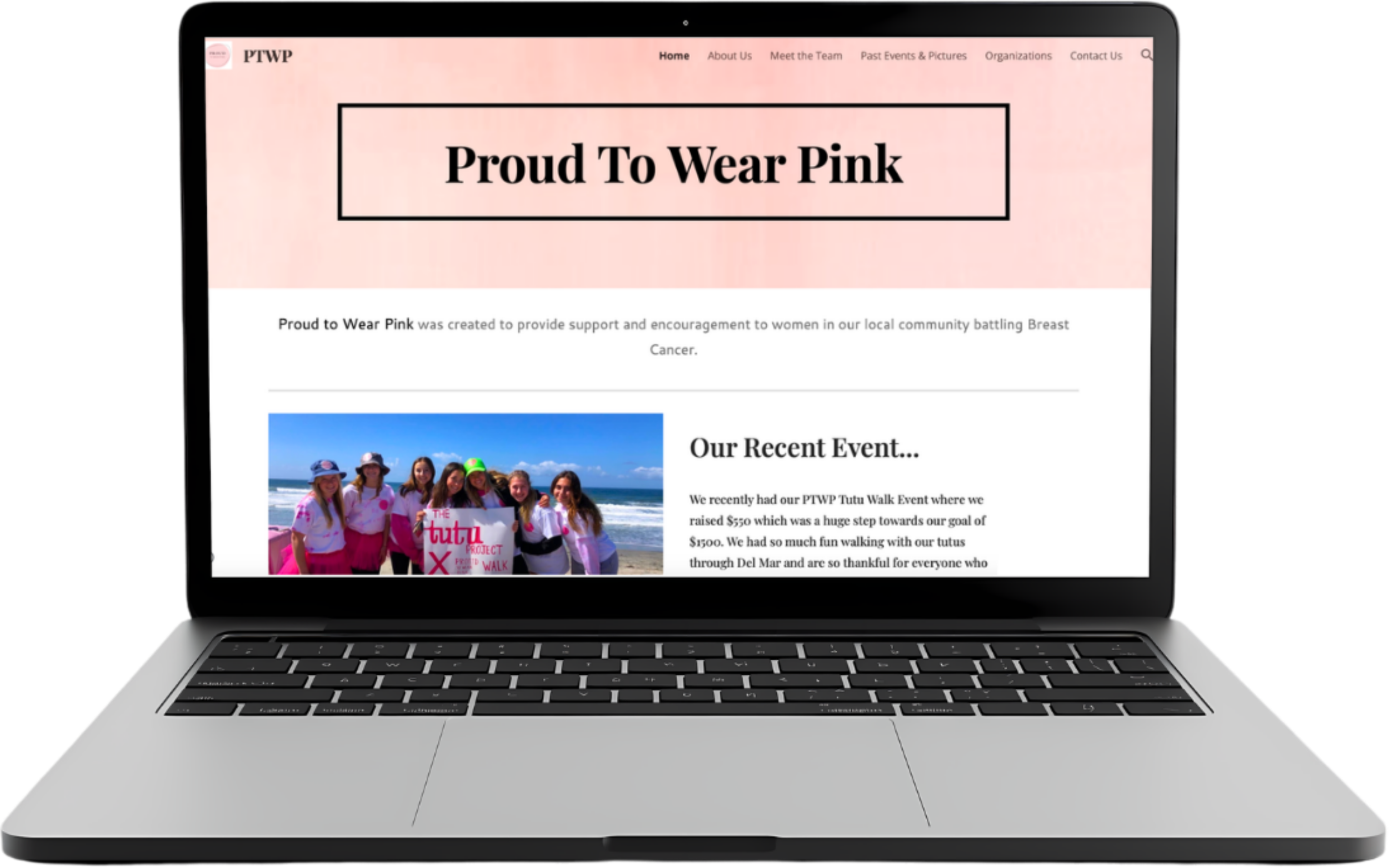 A laptop displaying a webpage with a pink background header that reads "Proud To Wear Pink" and a photo of women on a beach holding a banner. The webpage includes navigation links at the top and text about a breast cancer support event.