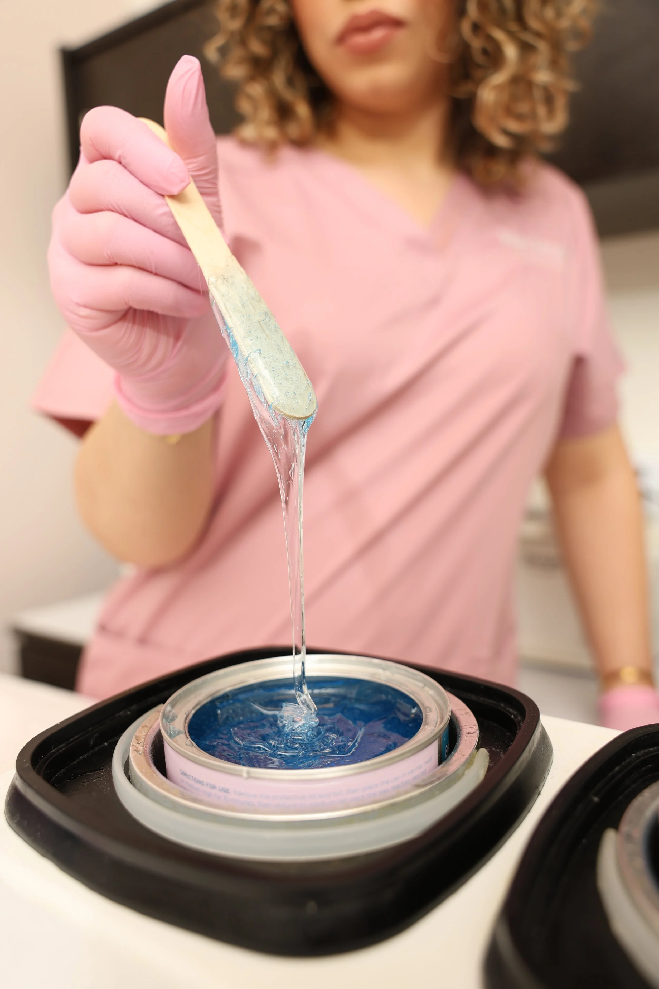 Wax specialist preparing professional wax for body waxing services at Wax Reveal by Carmen