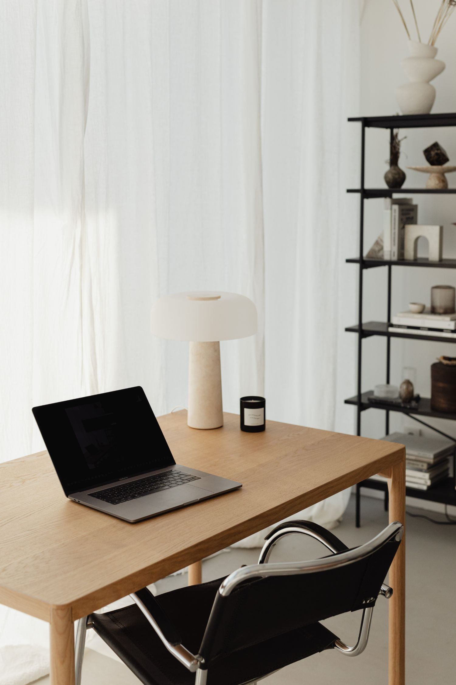 Laptop on a wooden table with a bookcase