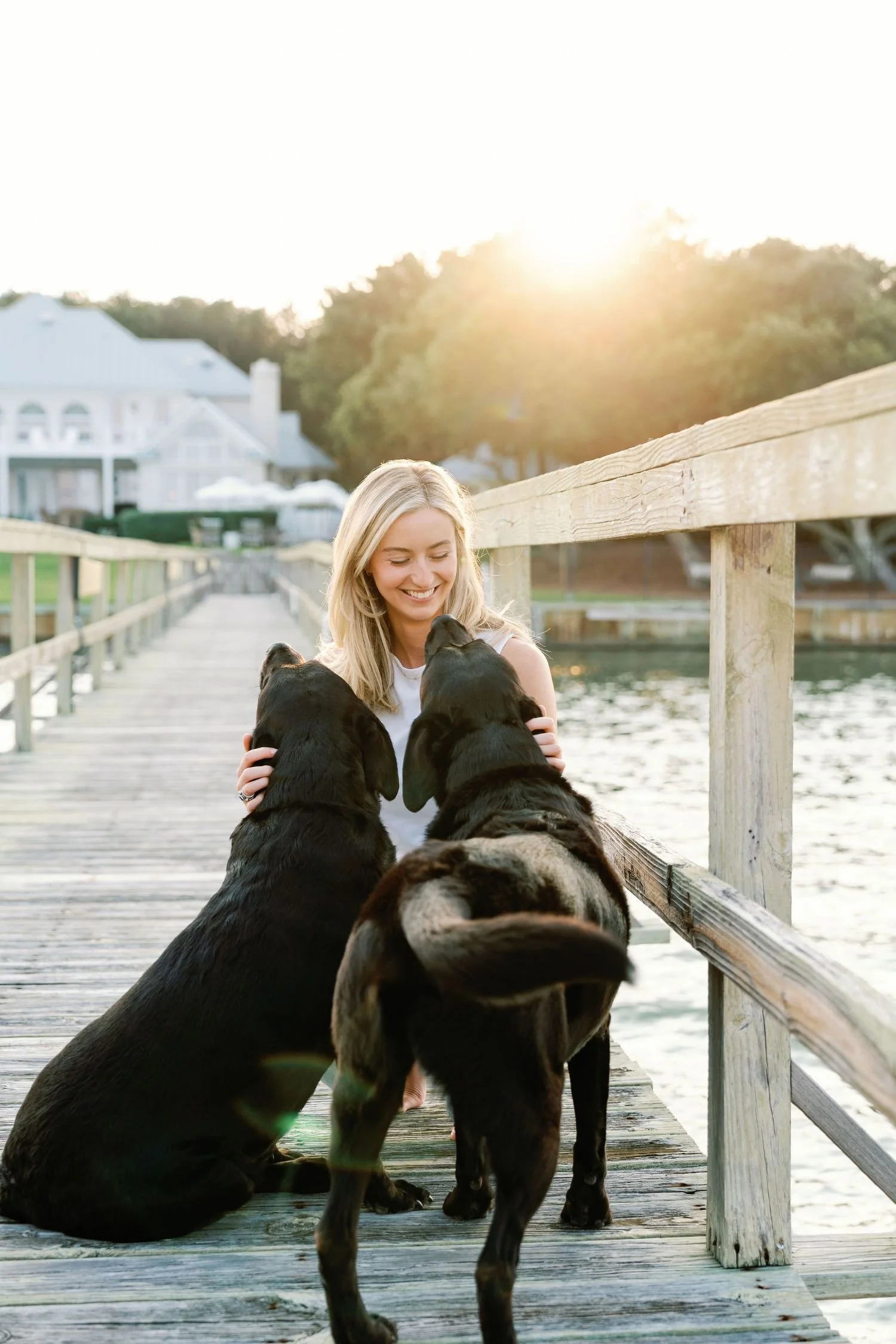Woman smiling looking at two black dogs