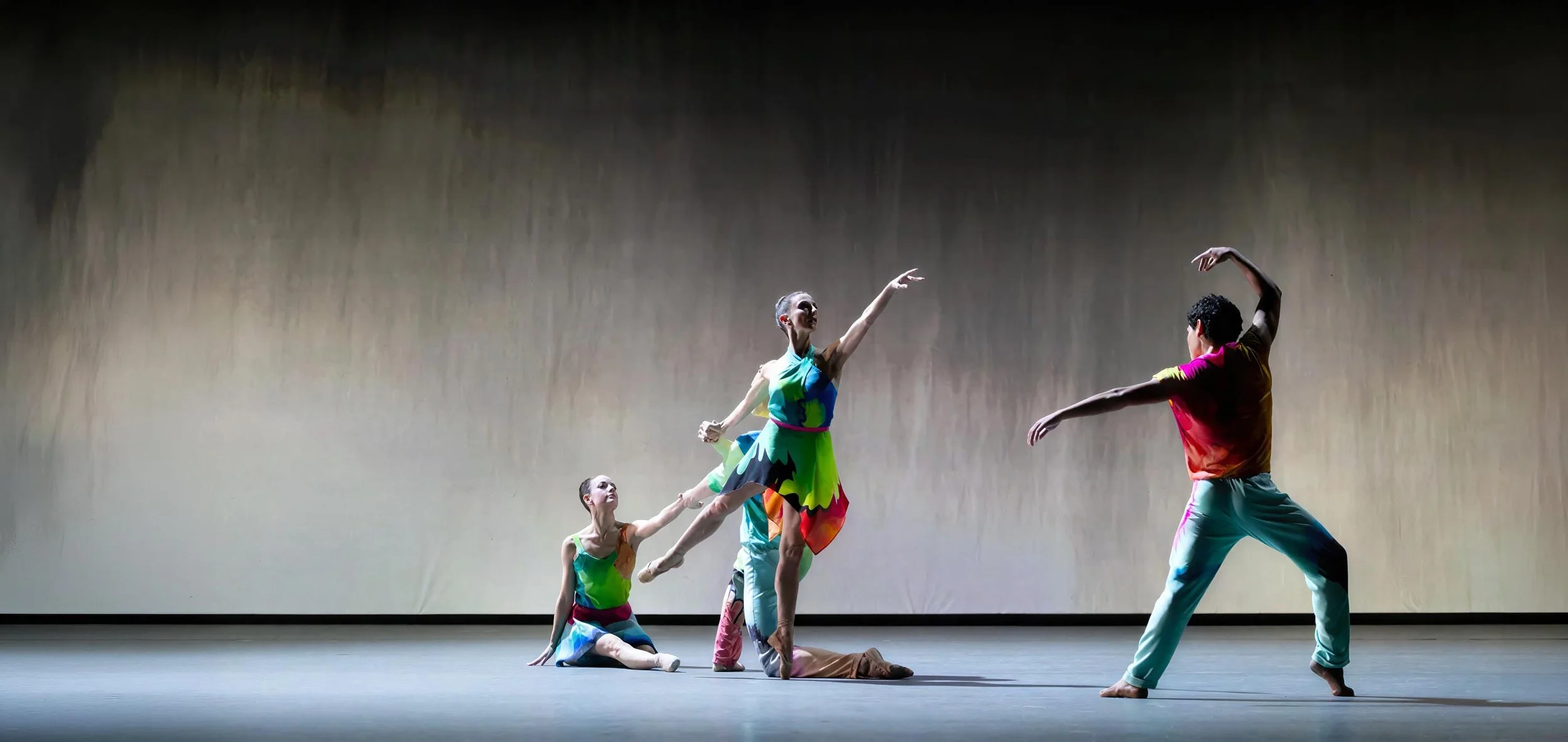 Dancers stretch and kneel across the stage in front of projected painted rain in soft gray — Petrichor, Miami City Ballet.