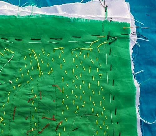 Fabric: green cloth with loose hand-stitching in yellow and black thread — Worn Stories, Netflix.