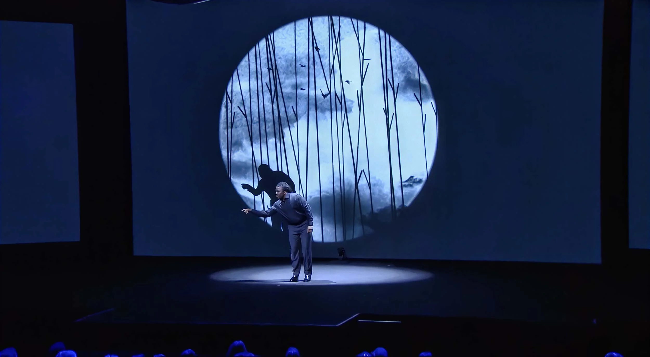 Darius performs in front of a projected circle of falling lines as a dark figure leaps above him — The Power of Proximity, Skoll World Forum.