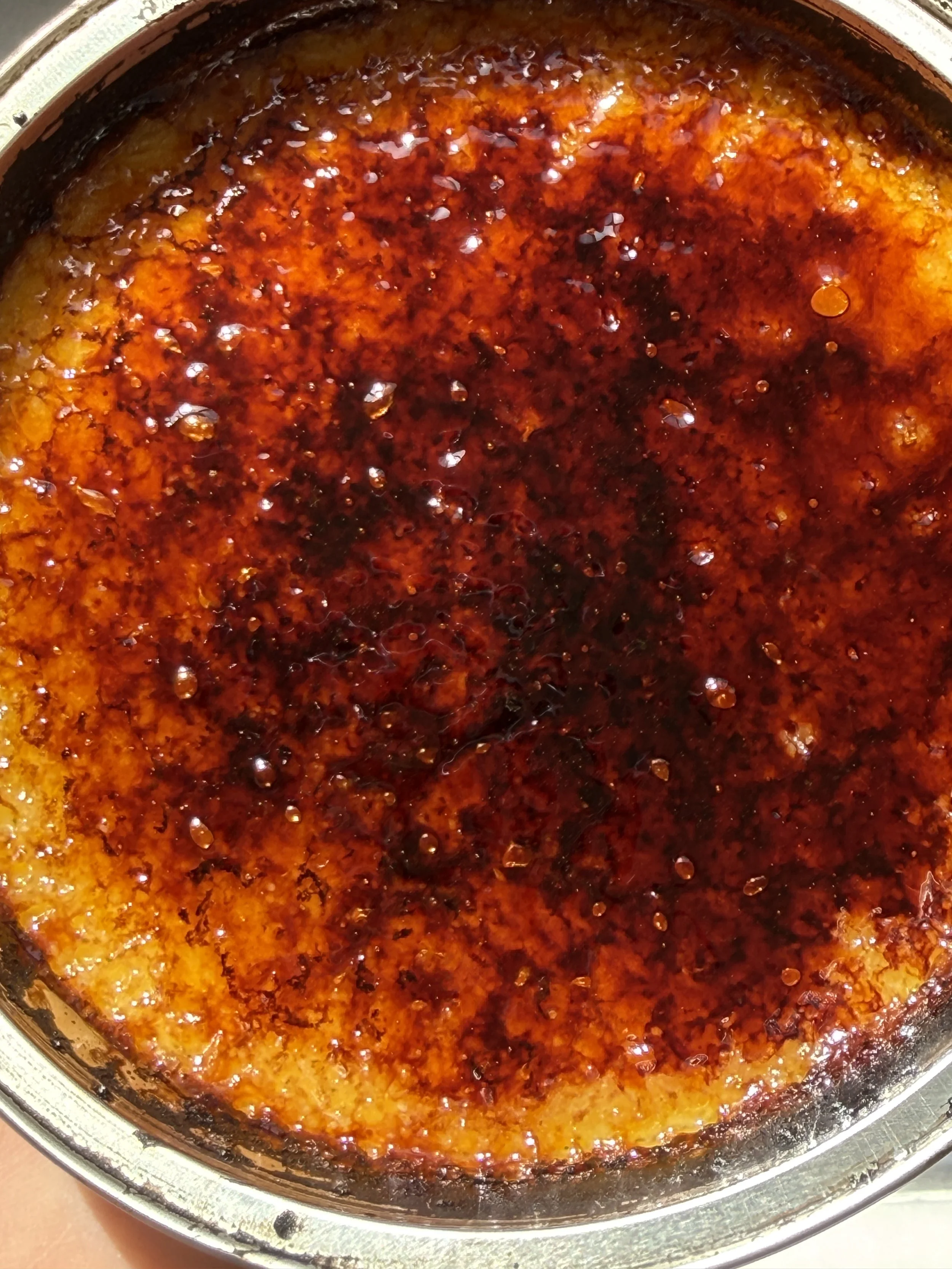 Burned sugar or caramel sauce inside a pan, with dark burnt spots and bubbling.